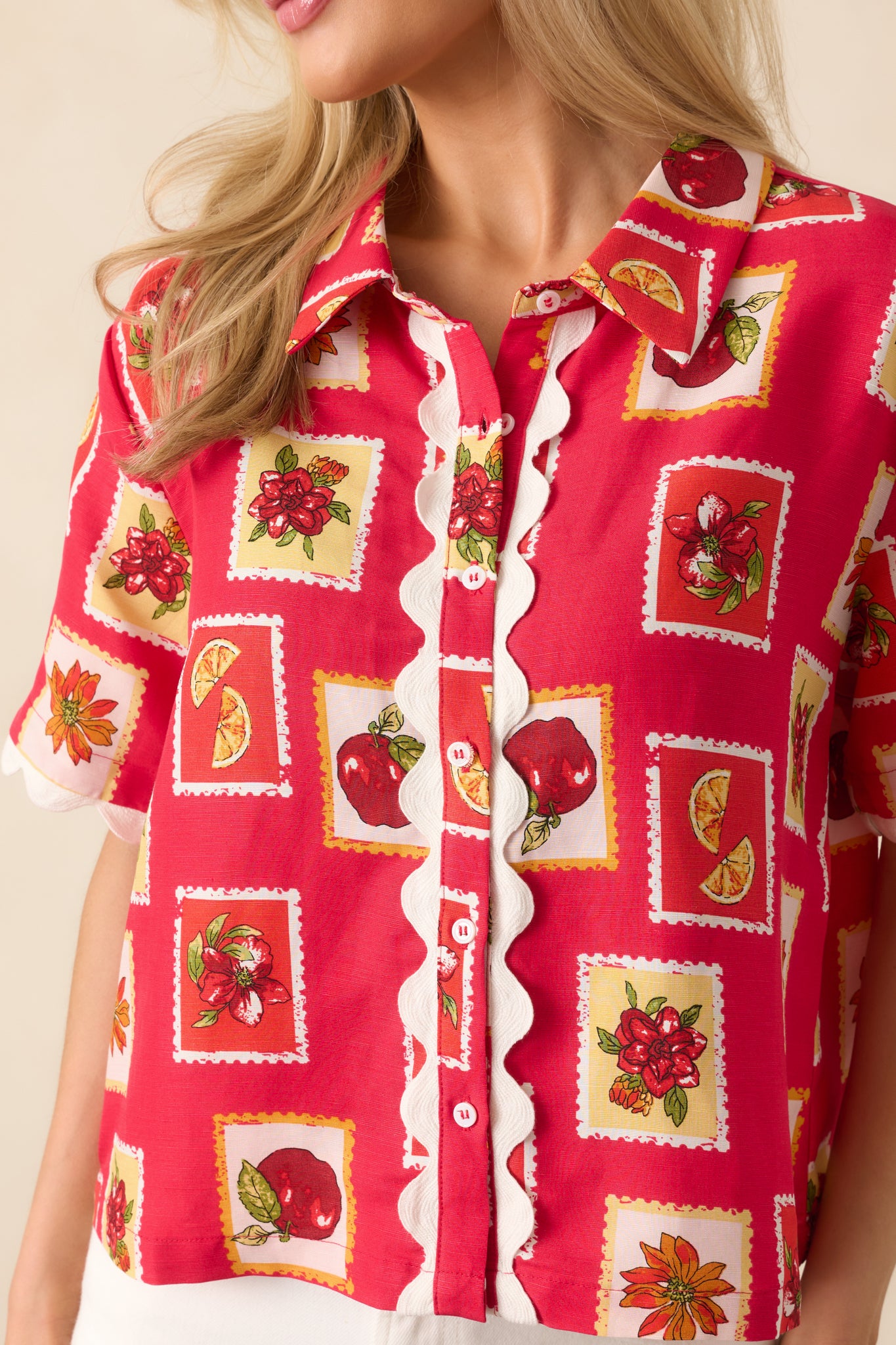 Detailed close-up showing the white scallop trim and intricate stamp-style patchwork print on the red linen-blend fabric.