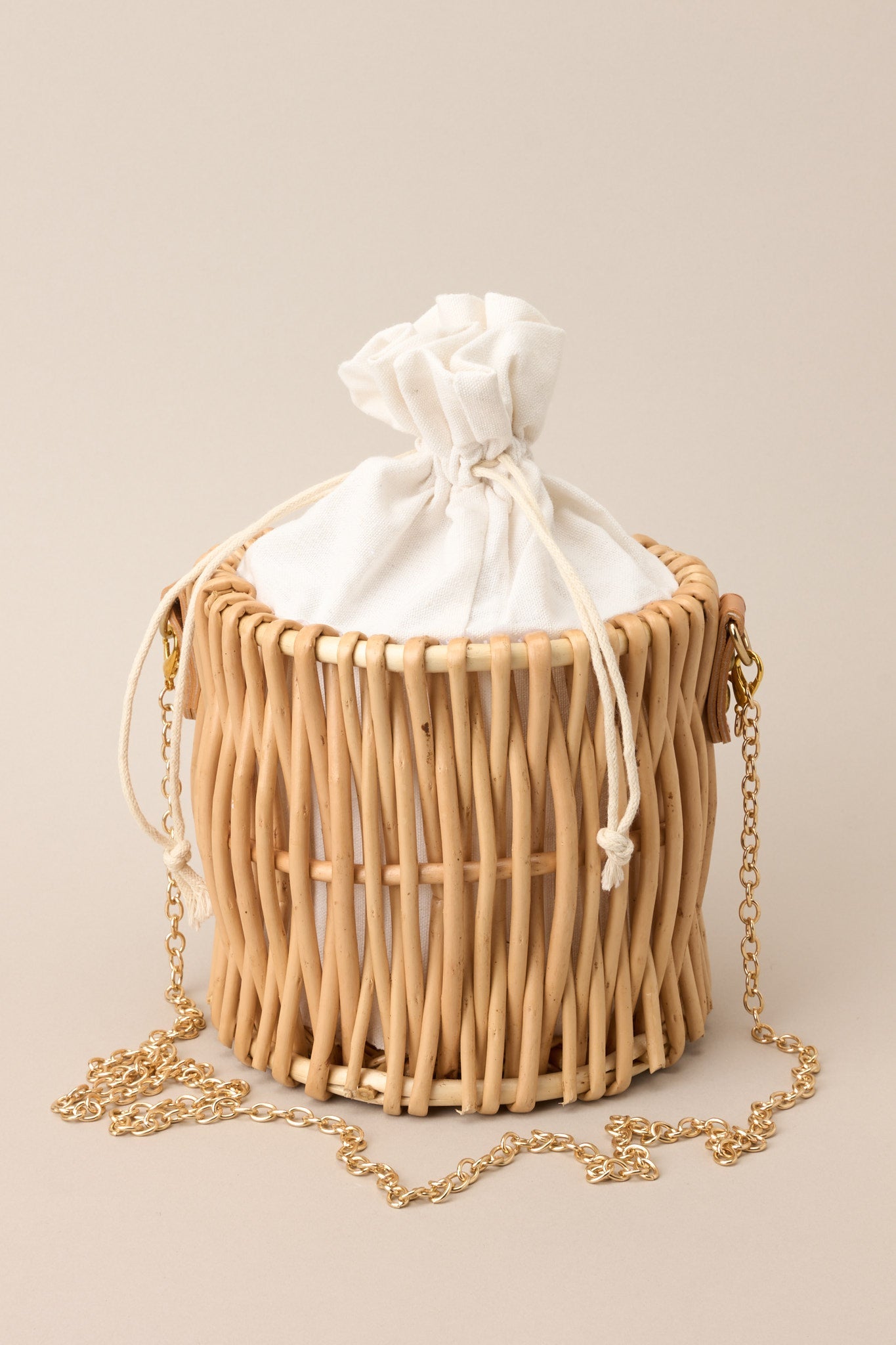 Detailed close-up of handbag showing woven wicker, gold hardware, and drawstring closure.