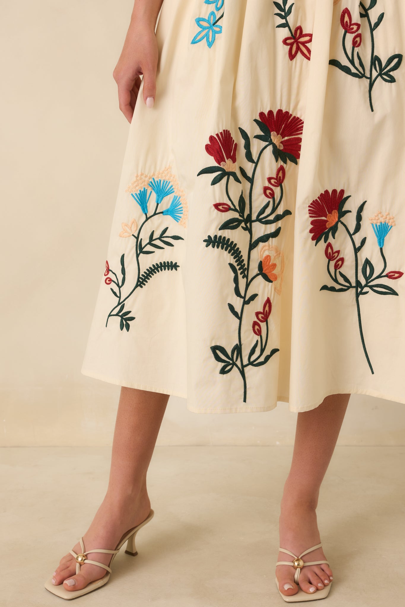 Detailed look at the floral embroidery, soft pleats, and fine stitching on the fully lined natural skirt.