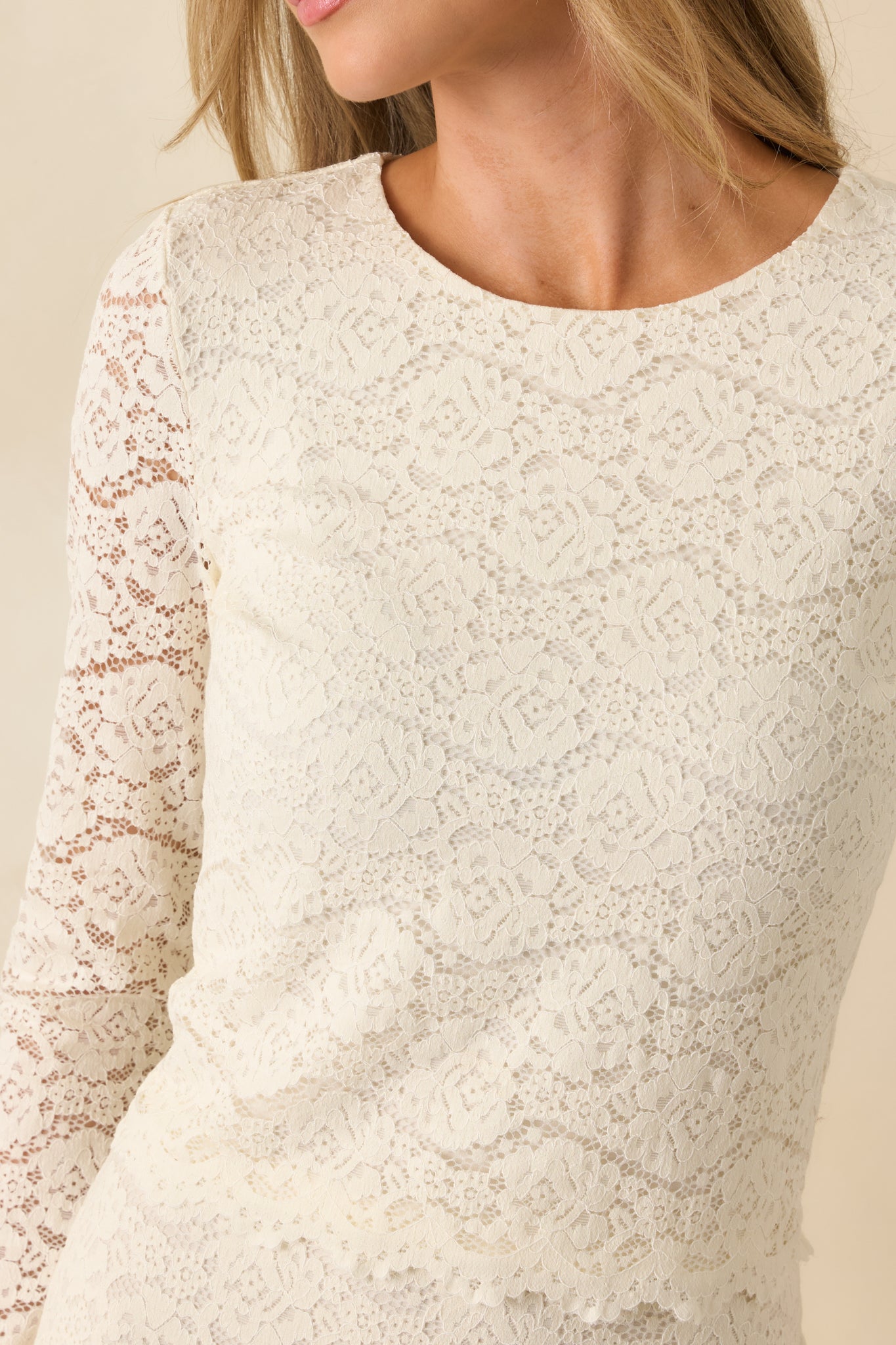 Detailed view of floral lace overlay, scalloped hem, and knit fabric texture.