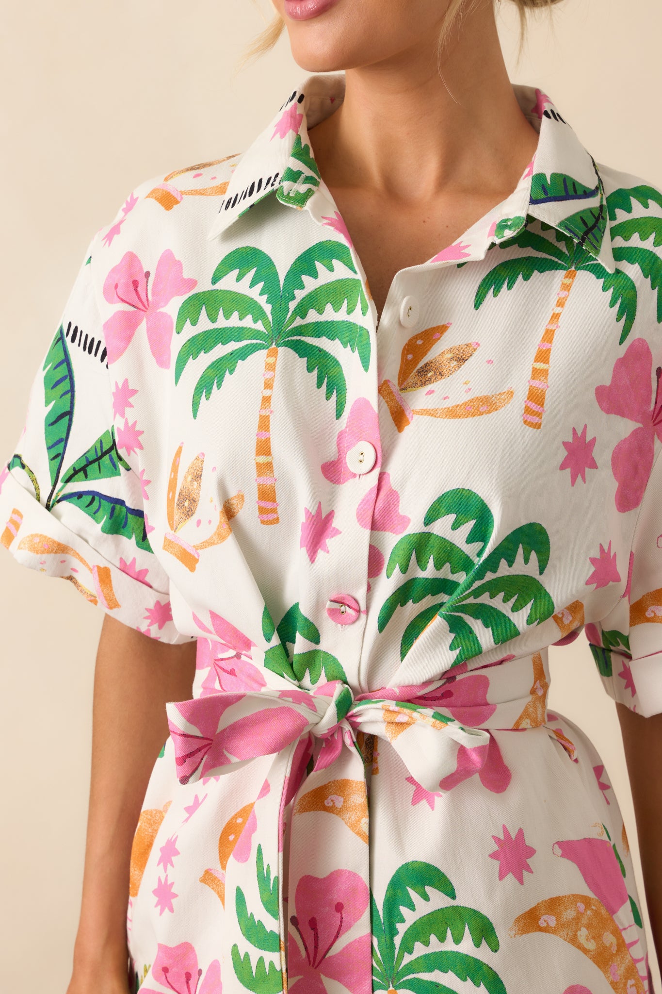 Detailed image of the cotton fabric texture and the vibrant tropical pattern surrounding the button placket.
