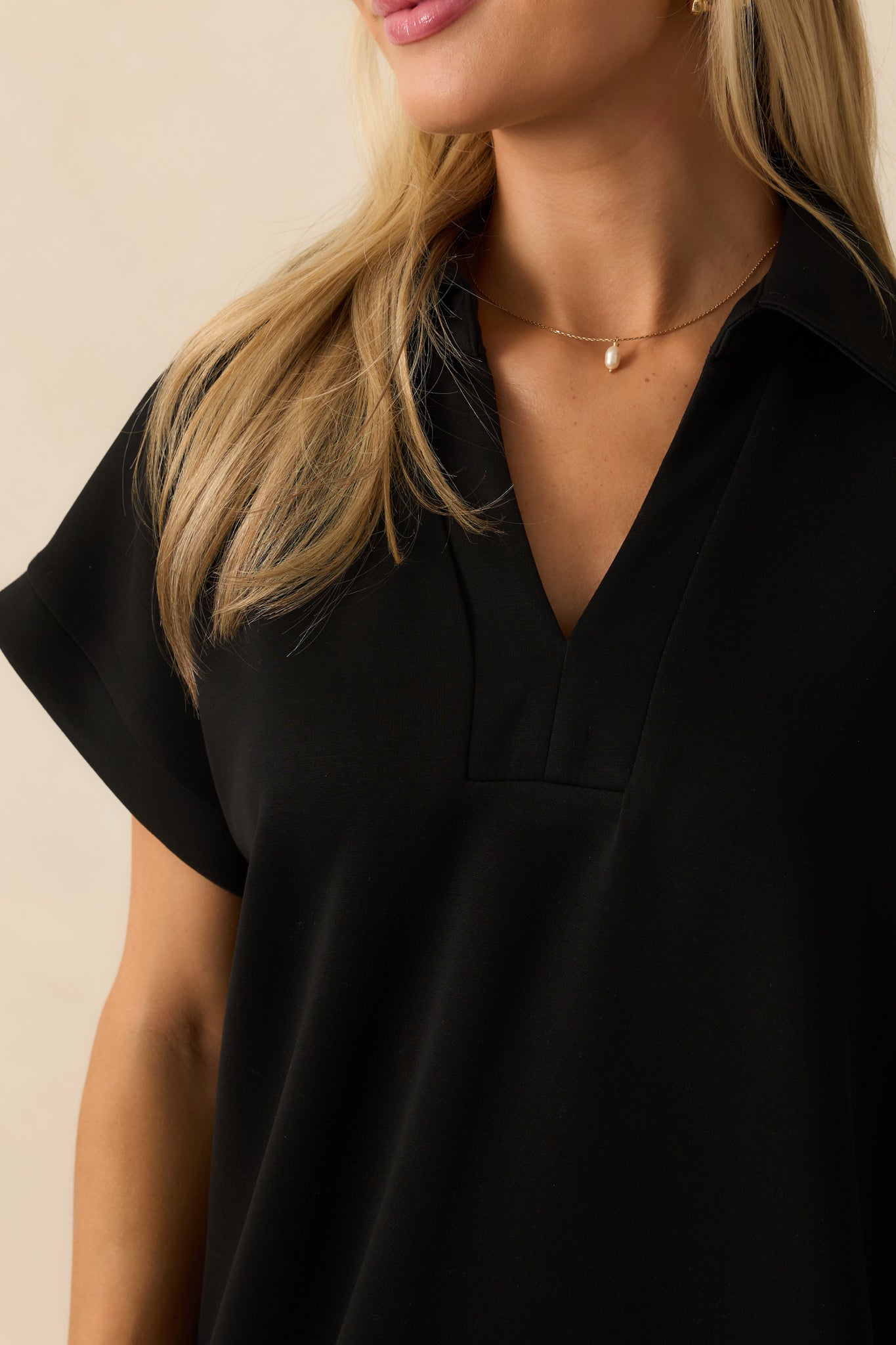 Detailed look at the buttery soft fabric and notch v-neckline of the black midi dress.
