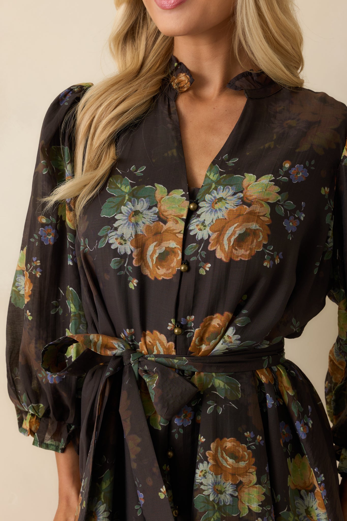Detailed view of the floral print, button-down front, and ruffled cuff design of the chocolate brown mini dress.
