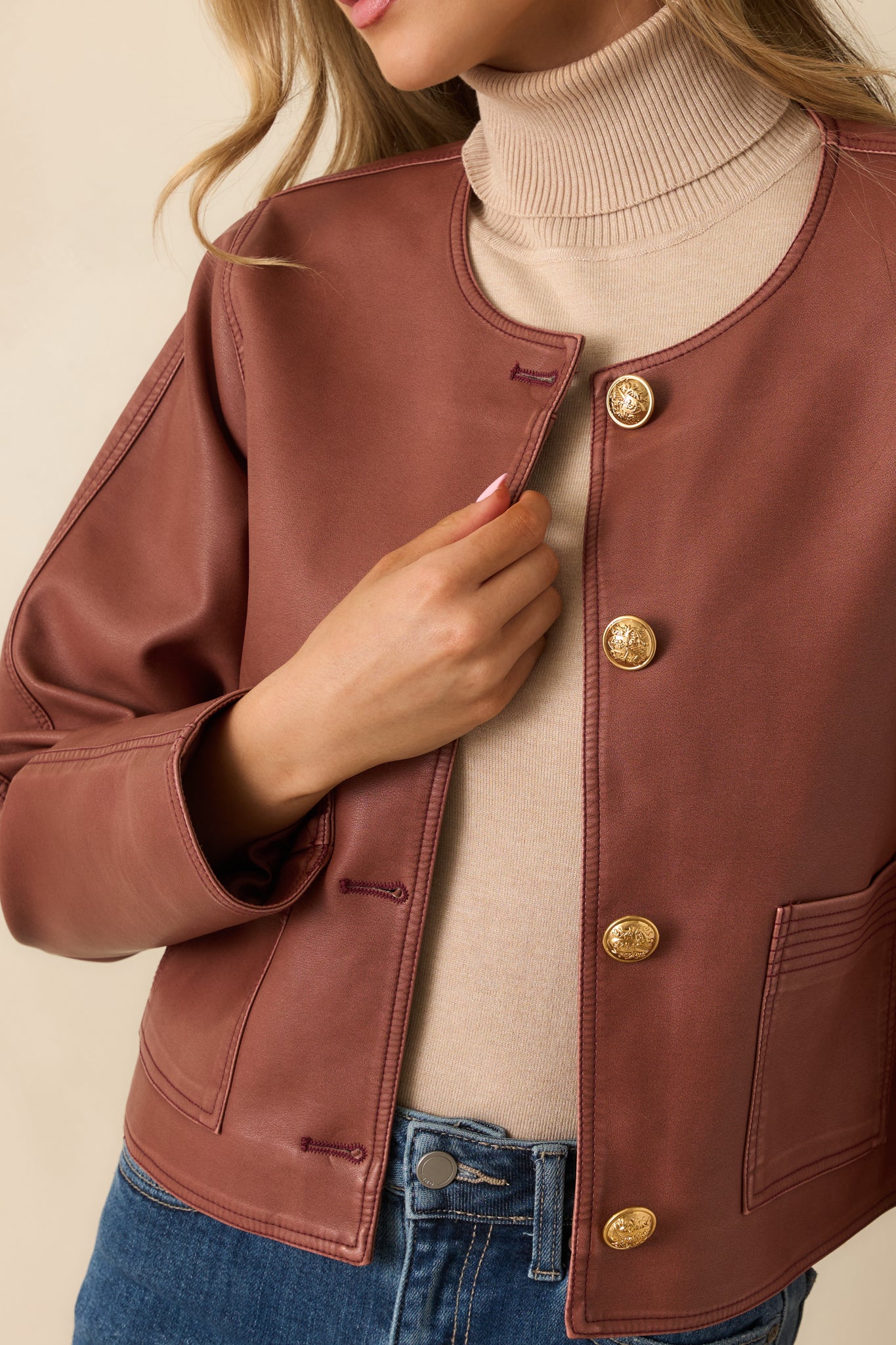 Detailed view of the embossed gold button closures and smooth faux leather finish.