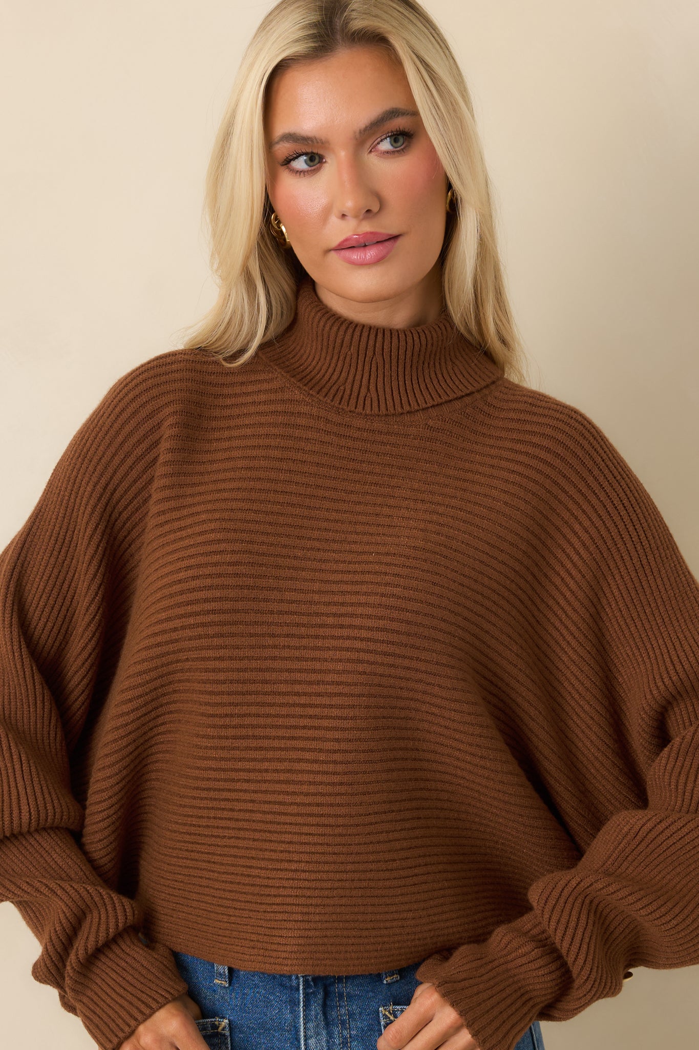Detailed view of brown sweater showing textured knit and draped sleeve design.