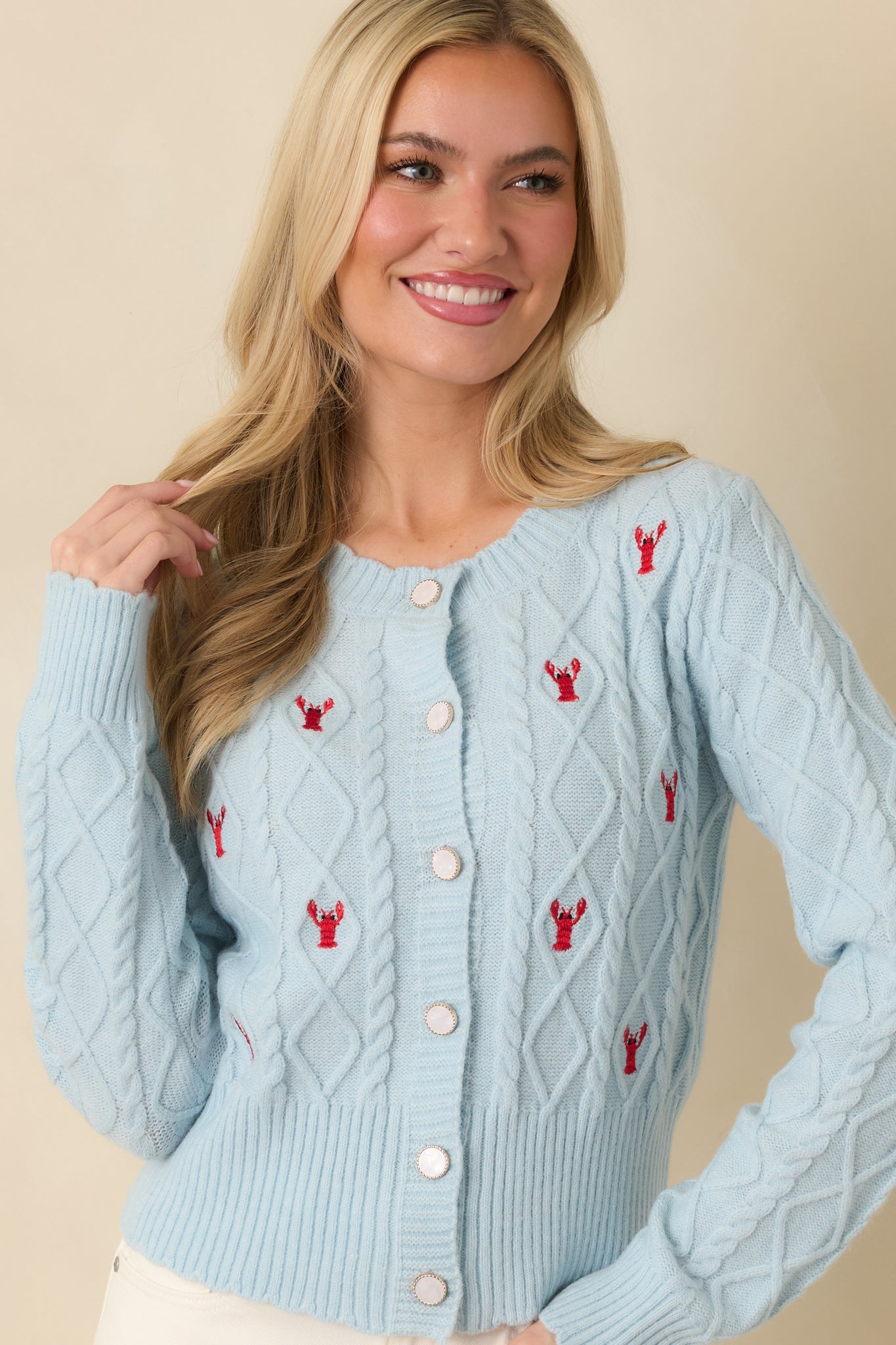 Detailed view of cardigan’s soft knit fabric with lobster embroidery around chest area.
