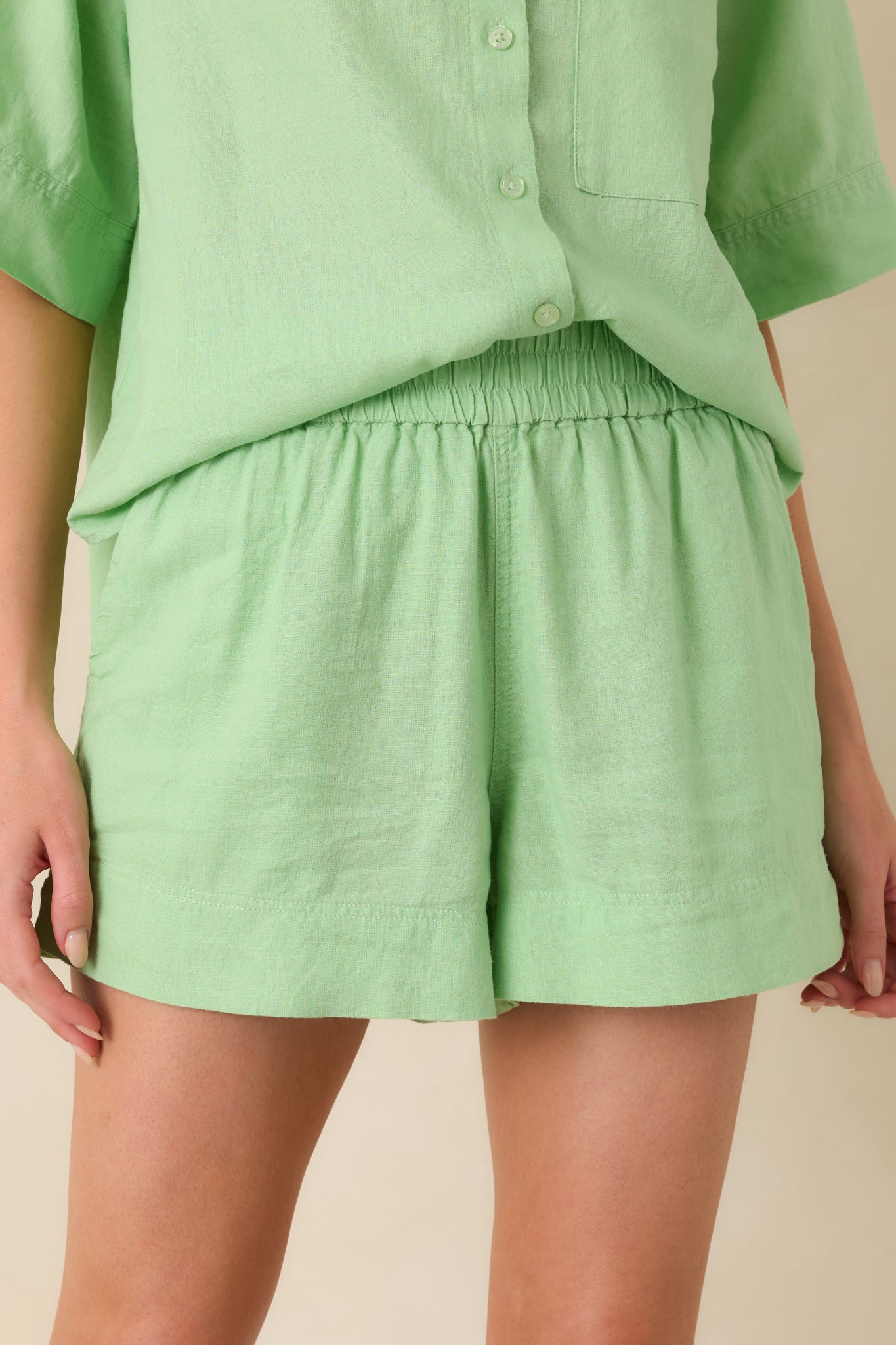 Detailed view of elastic waistband on soft light green shorts