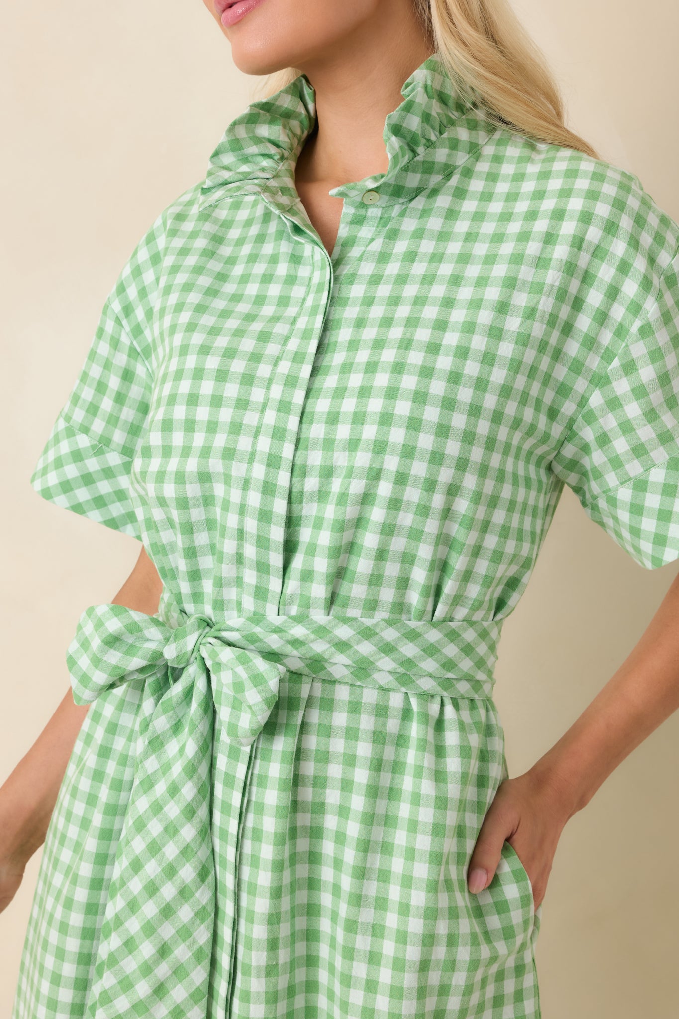 Detailed view of the button-front placket, ruffle collar, and woven gingham fabric, highlighting the tailored stitching and texture.