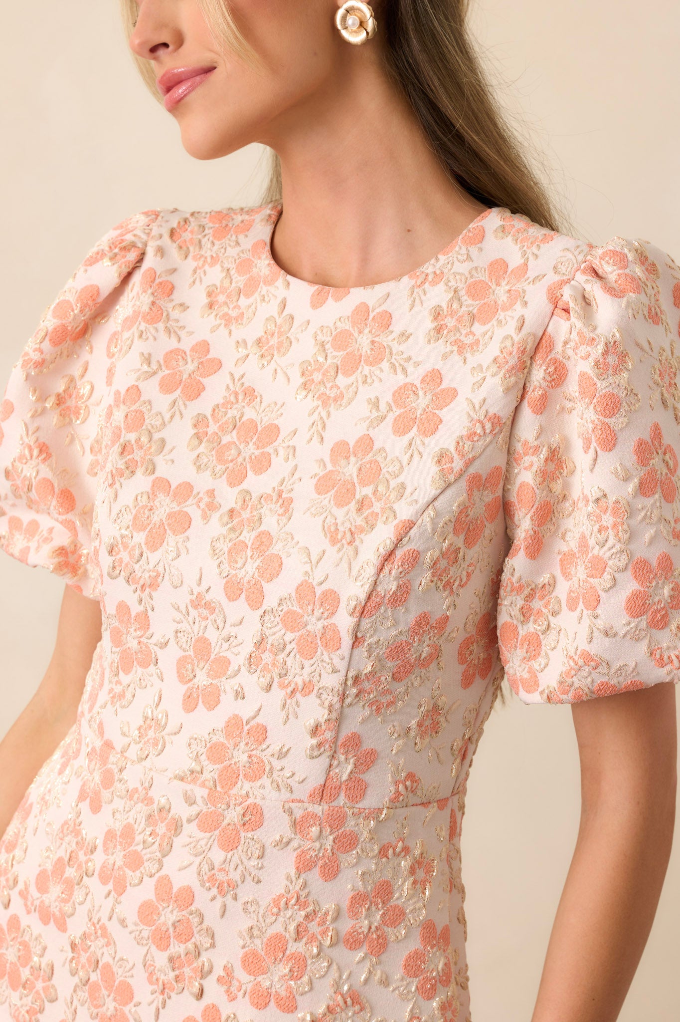 A detailed view of the gold accents on the apricot dress, showing the delicate shimmer and intricate placement of the embellishments against the soft fabric.