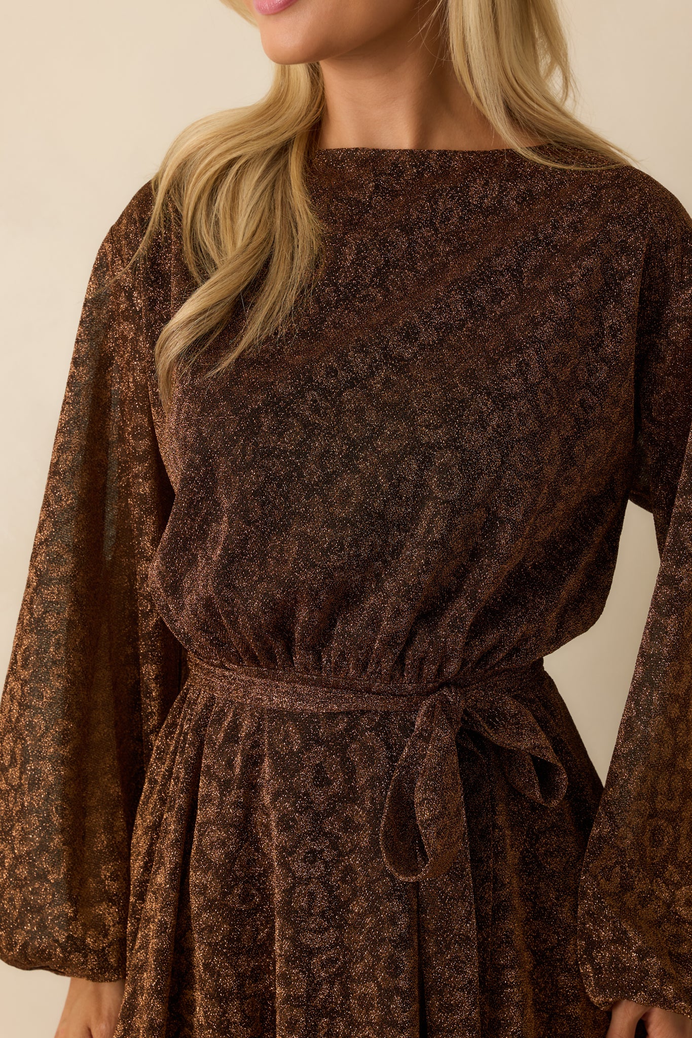 Detailed view of the subtle shimmer in the brown fabric and the removable tie belt at the elastic waist.