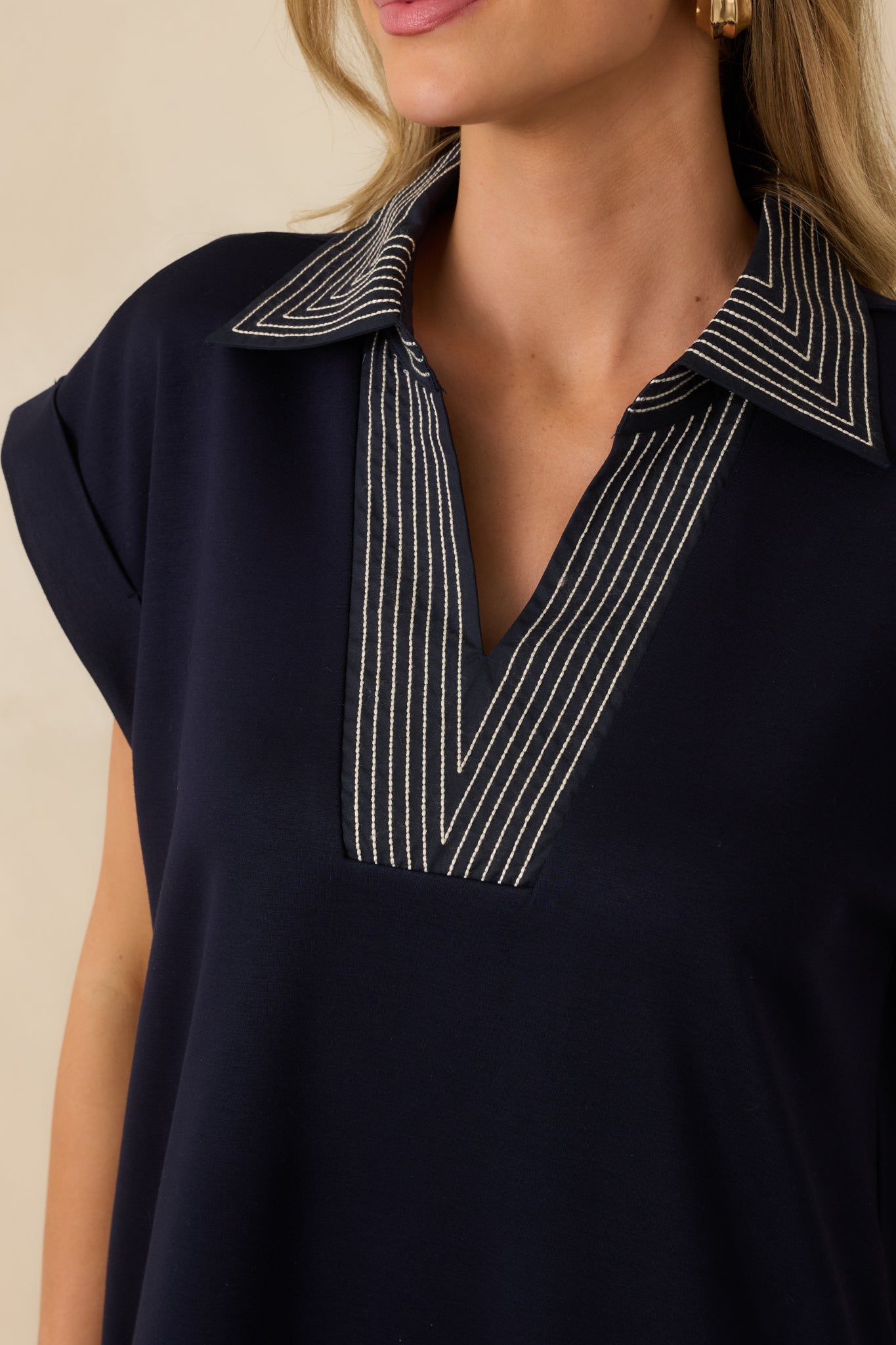 Detailed view of the navy knit midi dress highlighting the V-neckline and contrast stitch detailing.