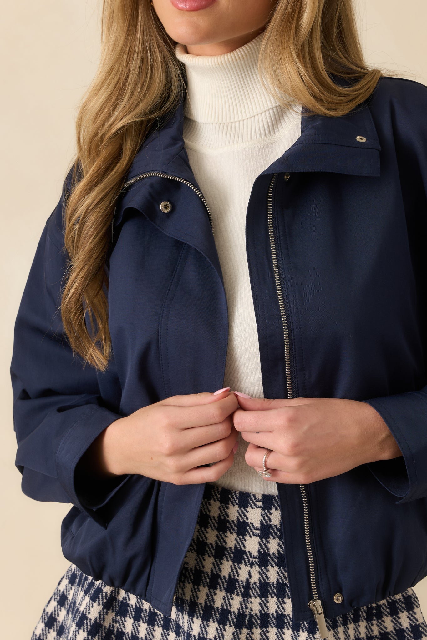 Detailed view of zip closure, snap collar, and smooth woven navy fabric texture.