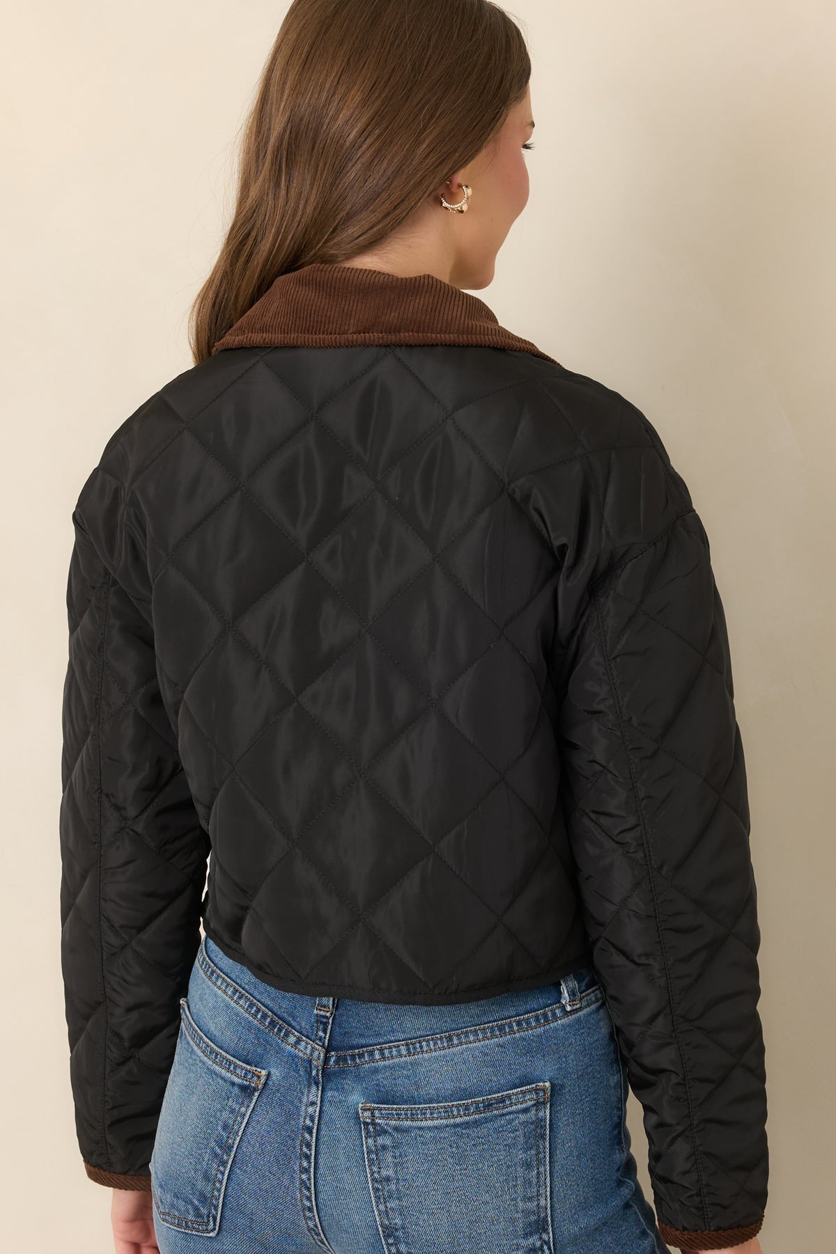 Rear of the diamond-stitched jacket showing the long sleeves, slightly cropped silhouette, and coordinating black lower-edge binding.
