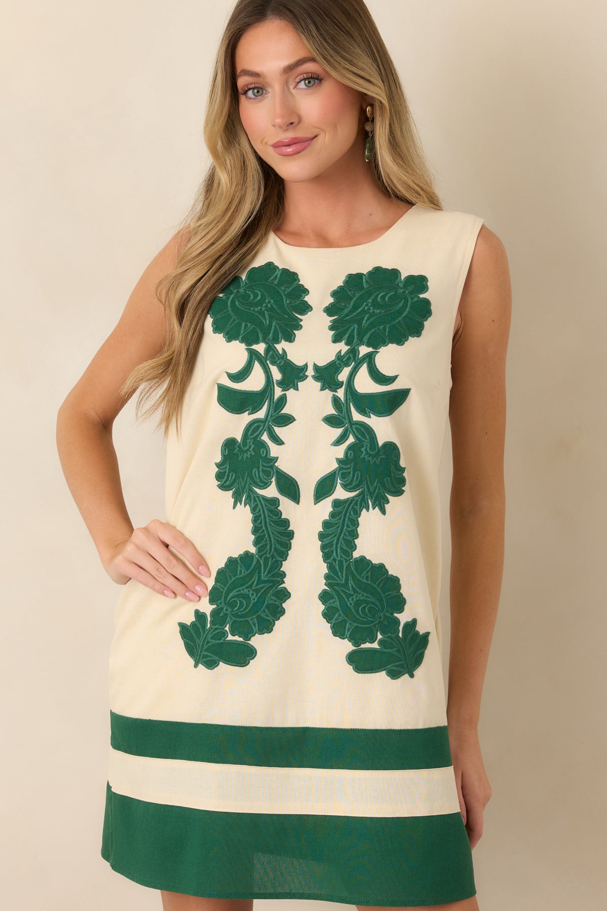 Dimensional green floral motifs stand out against the smooth ivory background, highlighting the dress's detailed craftsmanship.