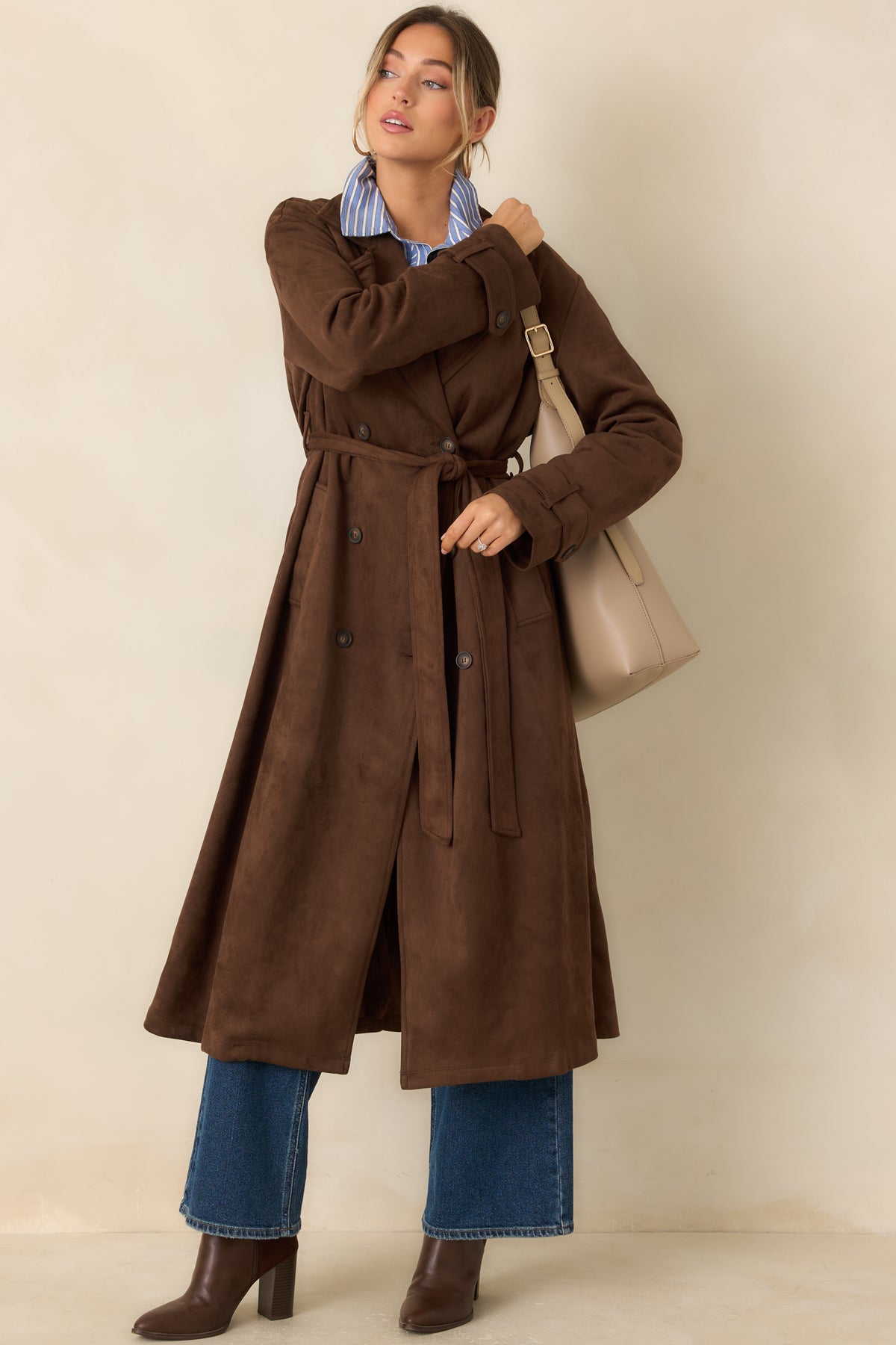 Double-breasted coat showcases a polished button front, adjustable tie belt, and long sleeves finished with buttoned cuff tabs.
