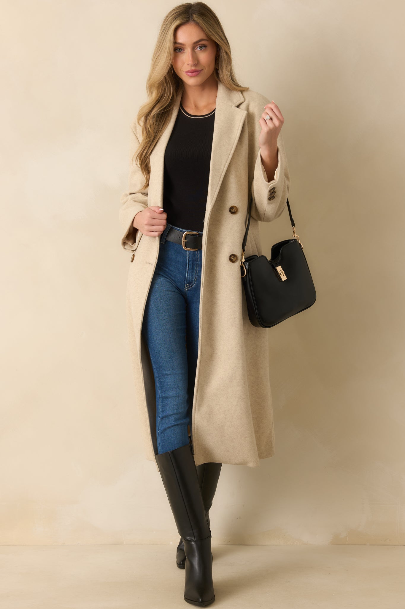 Double-breasted beige coat highlighted by its tortoise button front and tailored design for a timeless look.