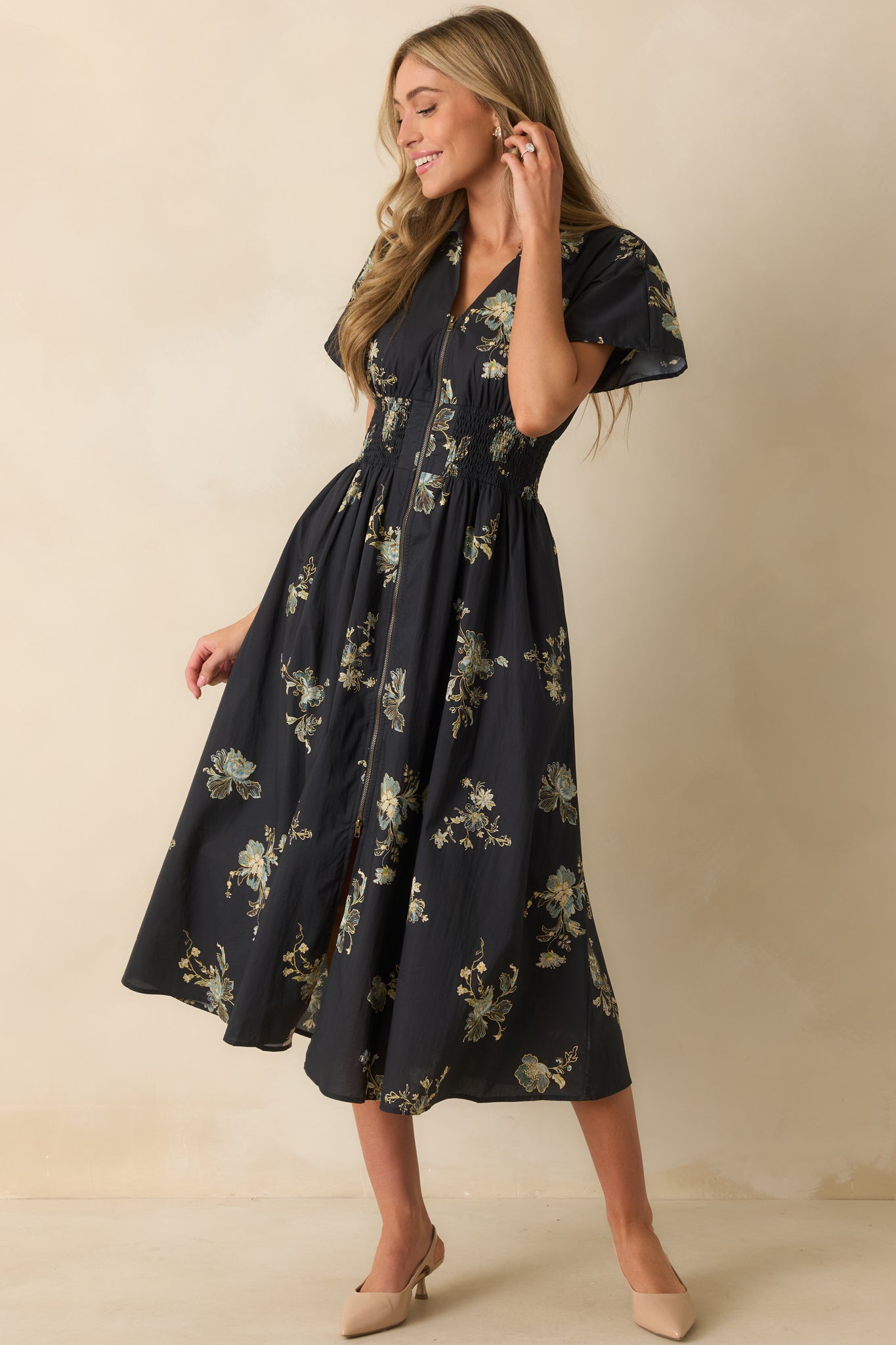 An angled front view highlighting the wide smocked waistband and functional front zipper closure.