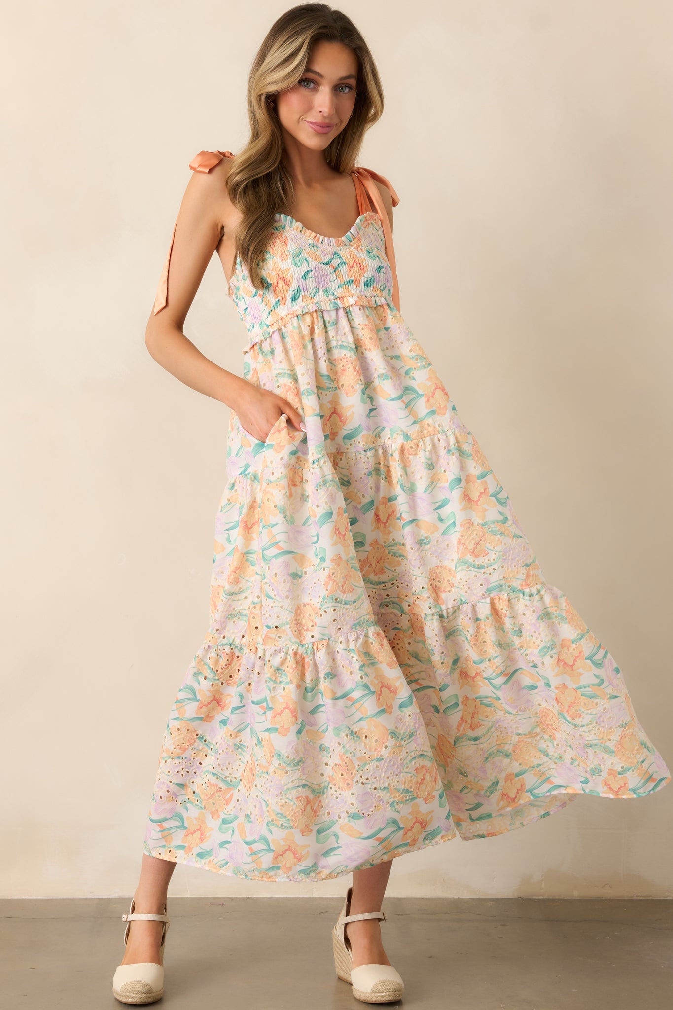 This dress features adjustable satin bow straps, a sweetheart neckline, and embroidered eyelet details, creating a light, romantic look.