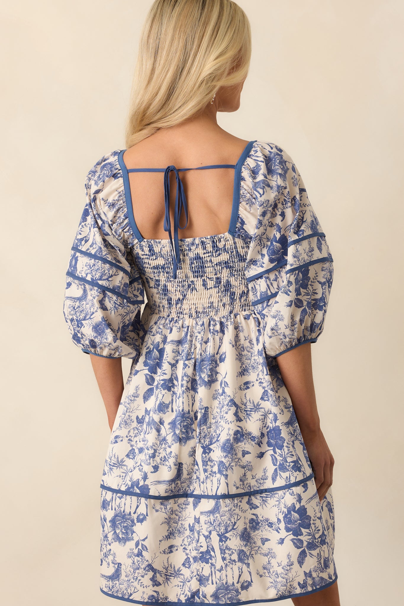 Rear view of the dress showcasing the puff sleeves from behind and the gentle tiers of the skirt with the floral pattern continuing across the back.