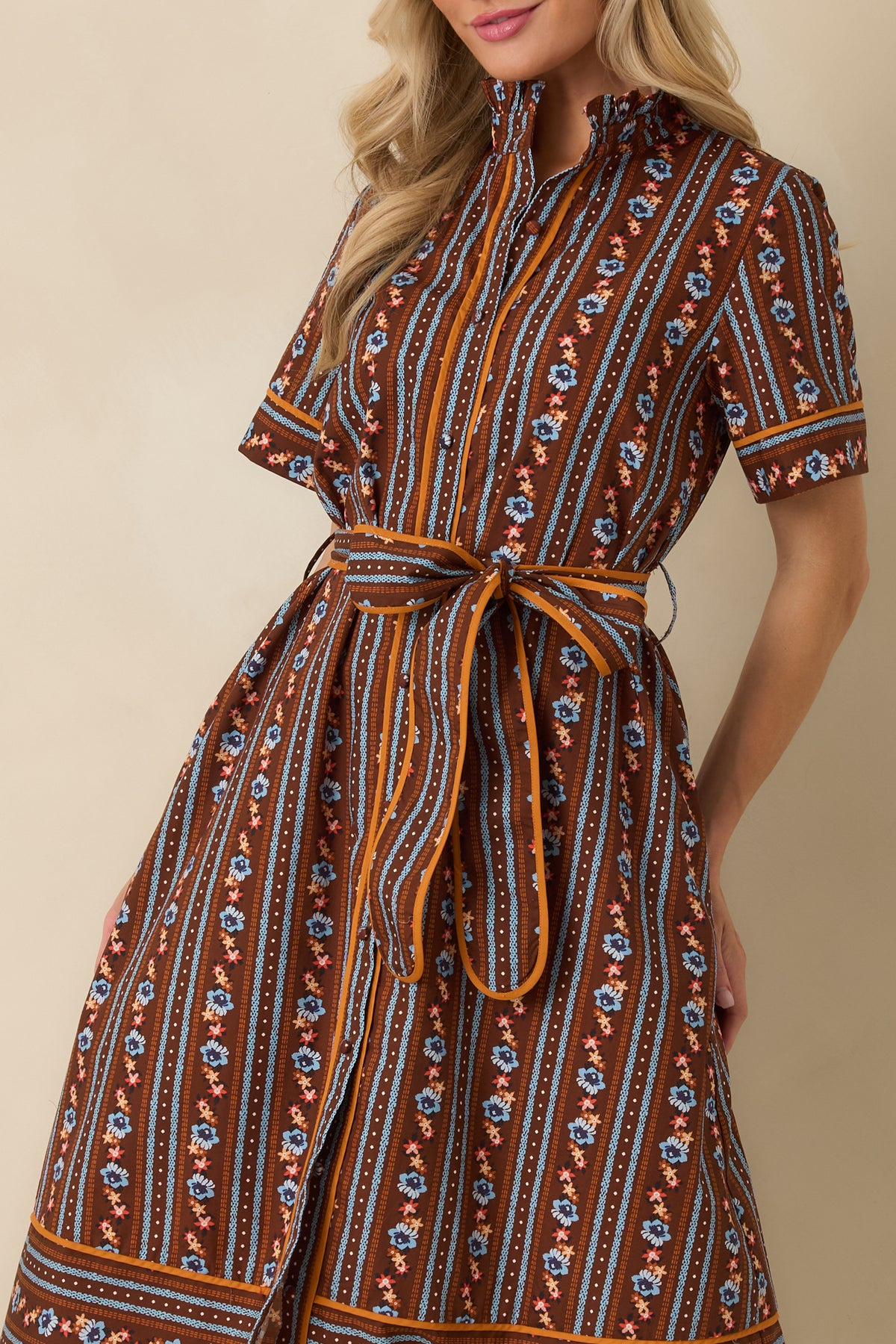 Close-up detail of the dress showing the ruffled stand collar, fabric-covered buttons, and alternating colorful stripe patterns.