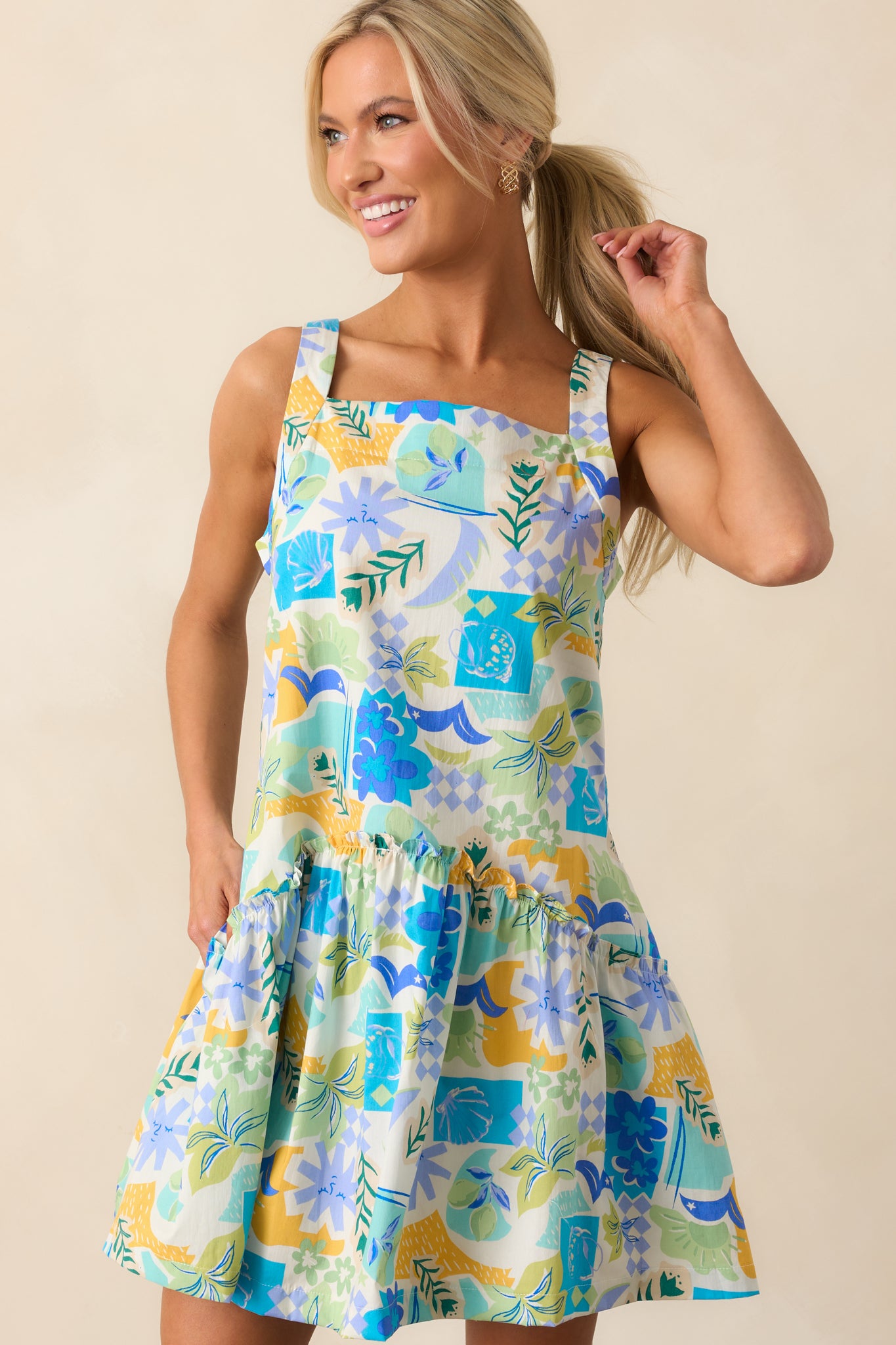 The colorful tropical print stands out against the bold blue fabric, highlighting the dress’s playful energy.