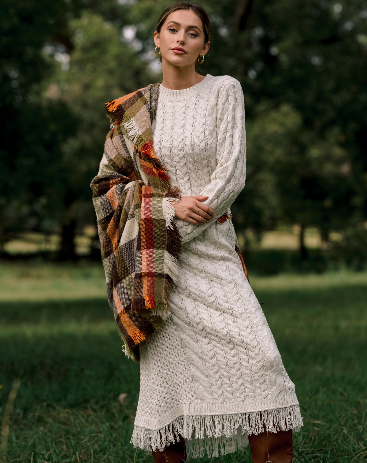 Model wearing a white knit maxi dress, with a plaid scarf over the shoulder.