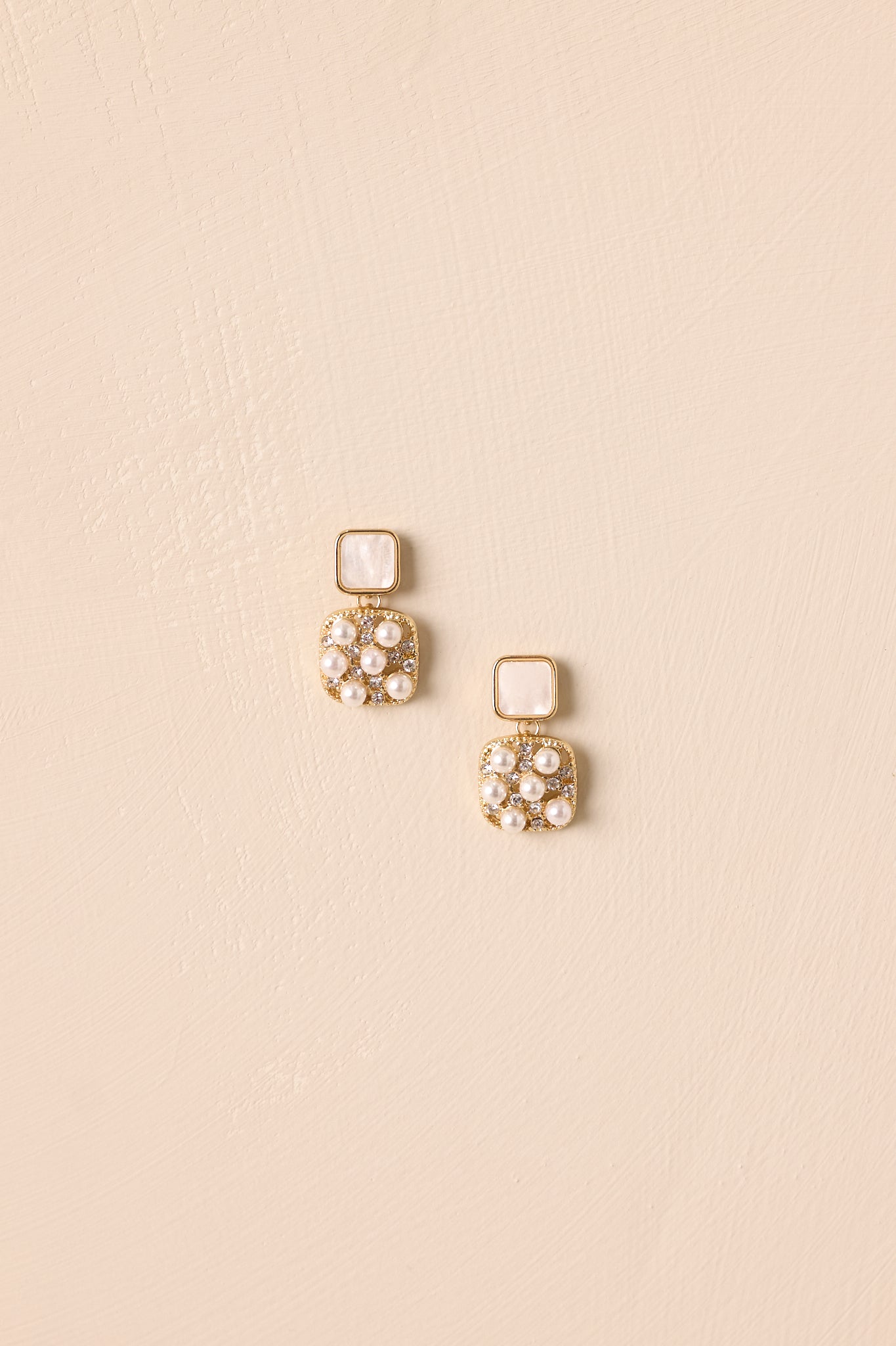 Drop earrings displayed against a beige background, showcasing the square pendant with pearl and rhinestone embellishments.