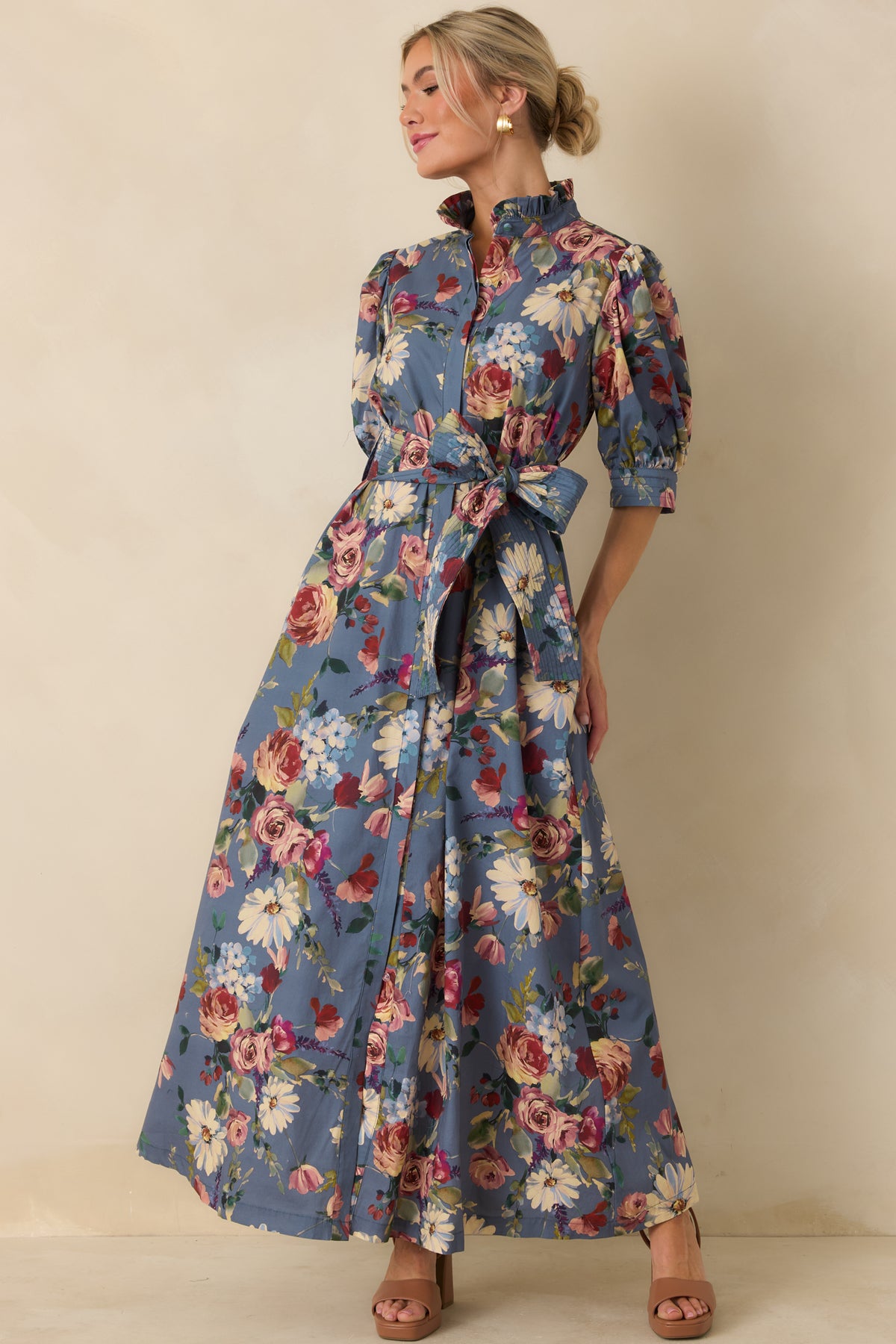 Dusty blue cotton maxi dress with a ruffled collar, defined waist, and sweeping A-line skirt.