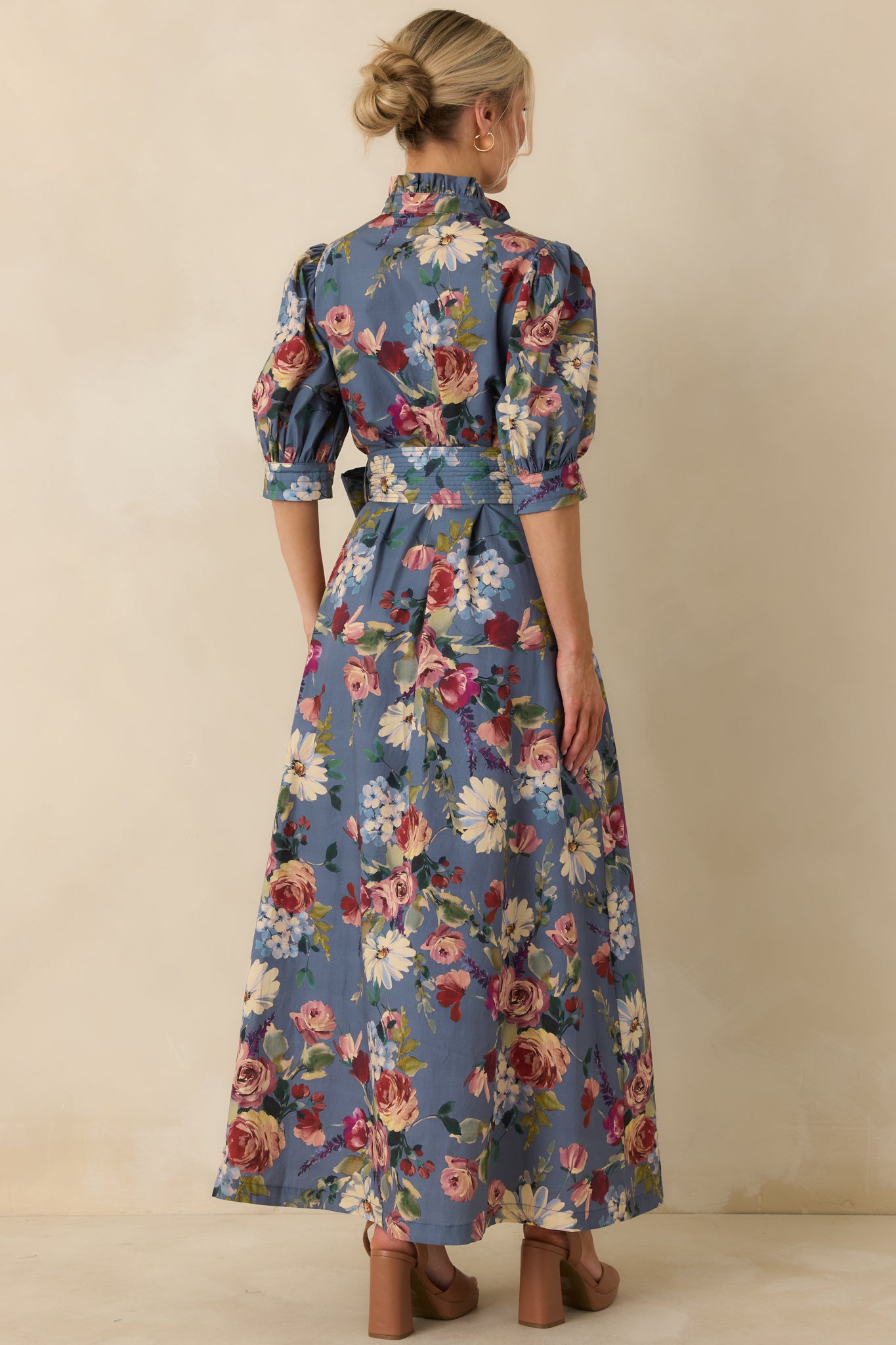 Rear view of the dusty blue floral maxi dress showing its sweeping A-line skirt and puffed sleeves.