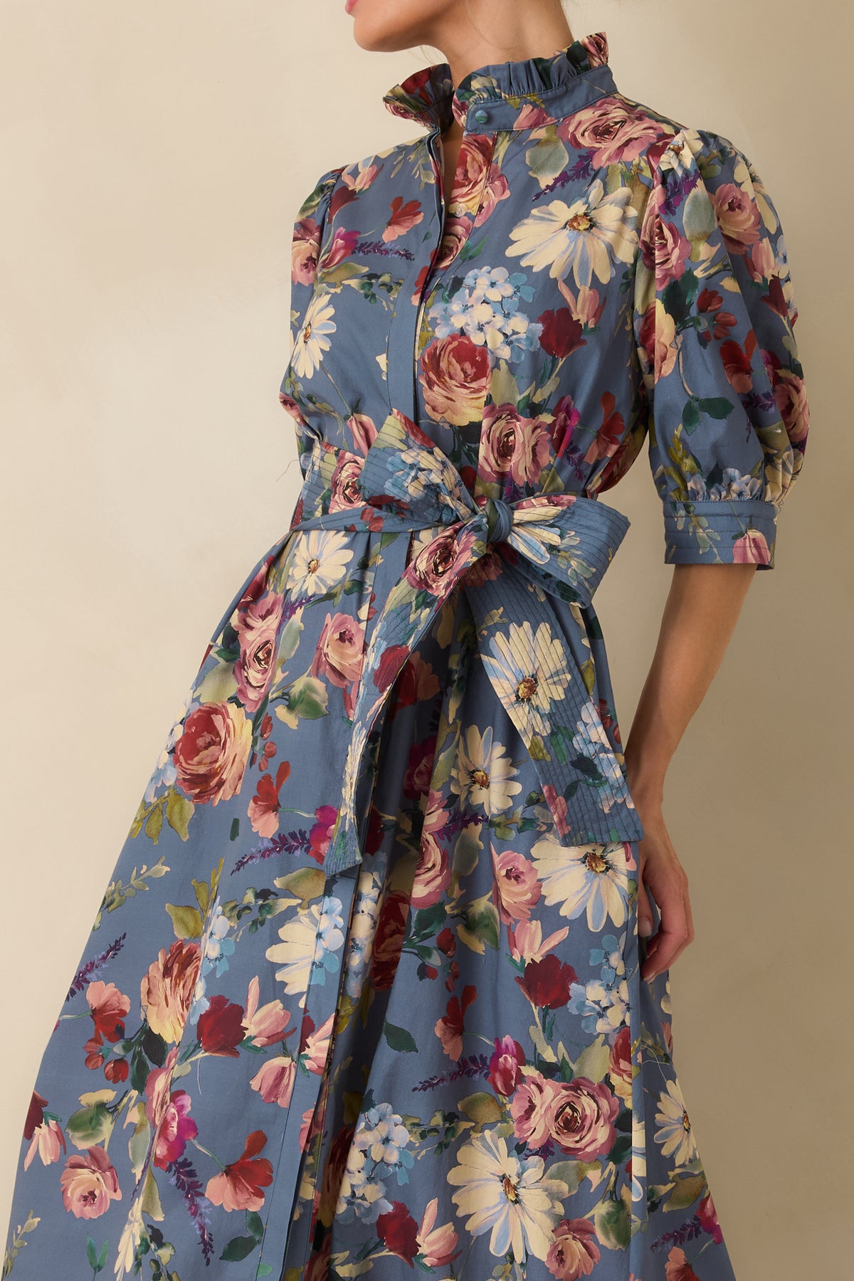 Close-up of the dusty blue floral maxi dress showing roses, daisies, hydrangeas, and ruffled collar detailing.