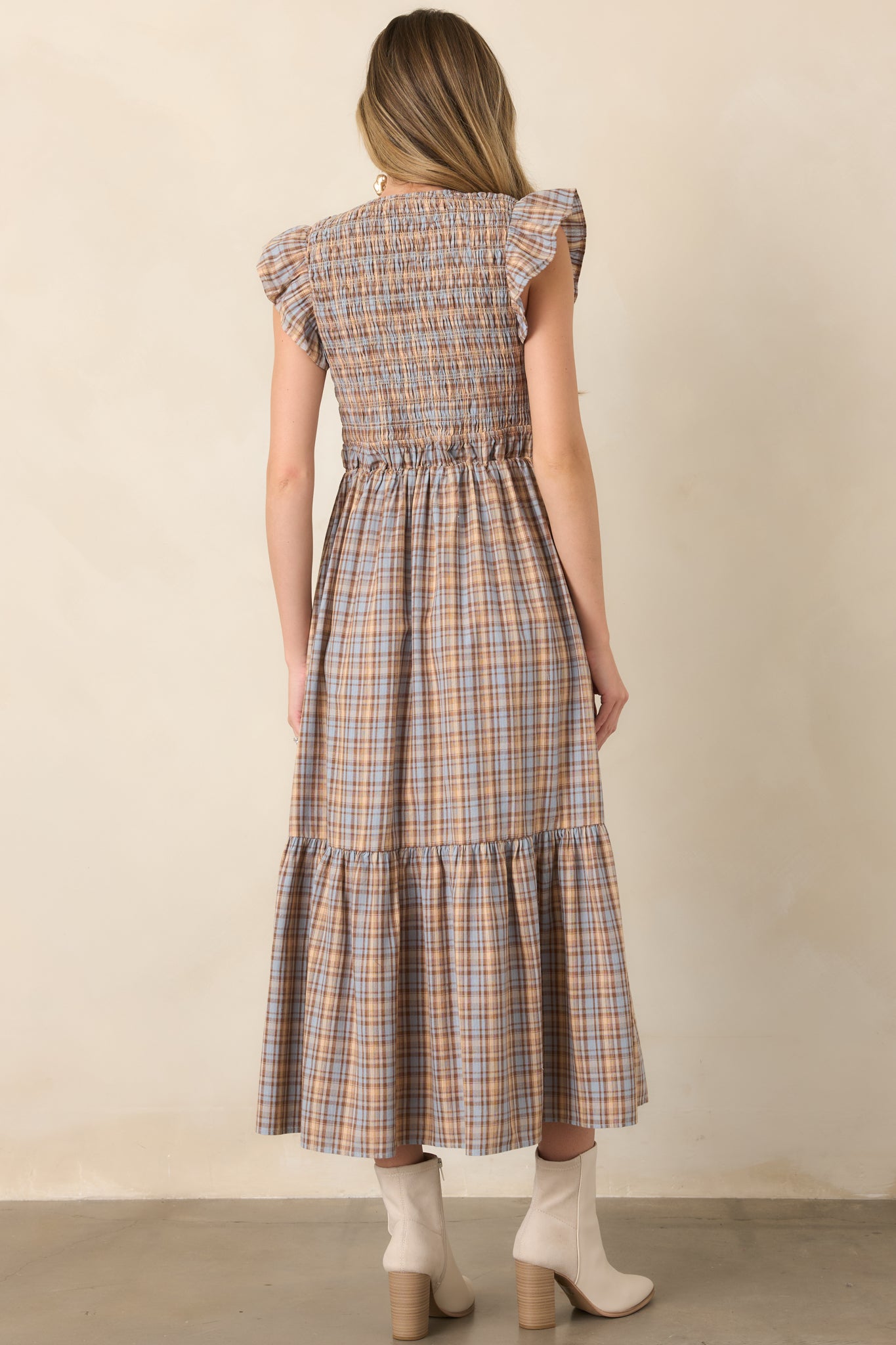 Rear view of the dusty blue plaid midi dress showcasing its smocked bodice, flutter sleeves, defined waist, and flowing gathered skirt.