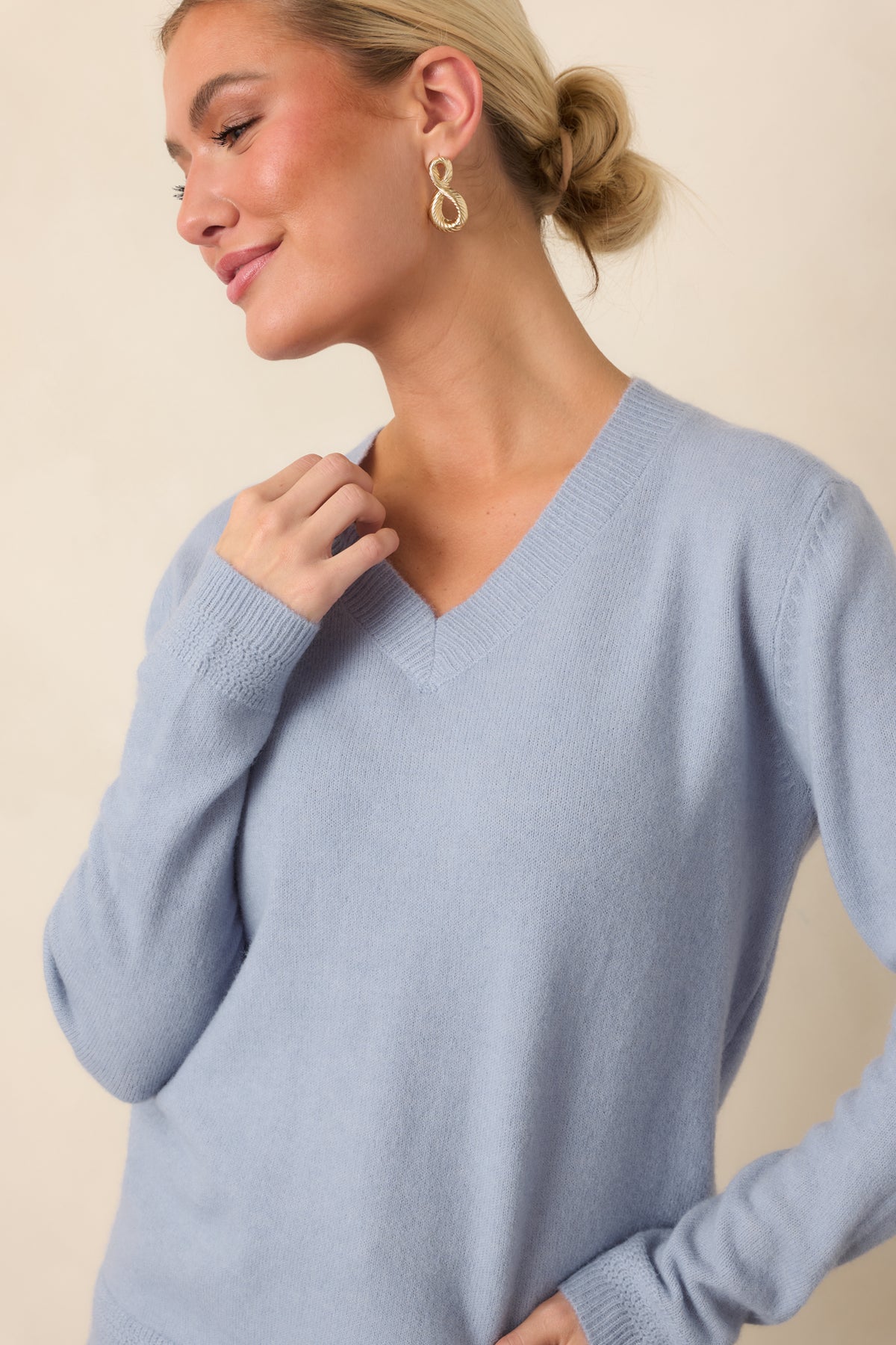 Dusty blue knit top highlighting the V-neckline and ribbed neckline trim.