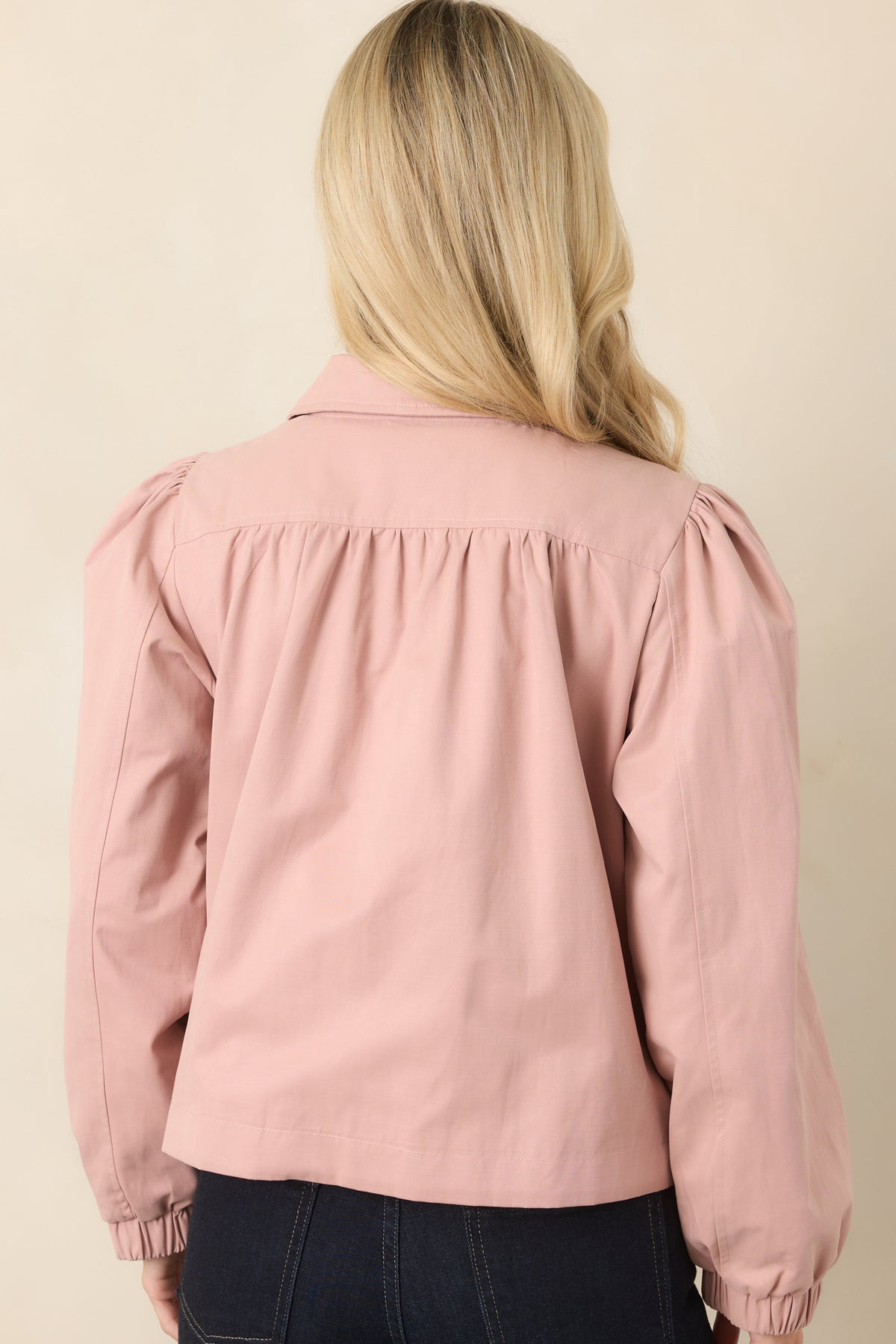 Rear of the dusty pink cropped jacket with gathered shoulders, puff sleeves, and elasticized cuffs.