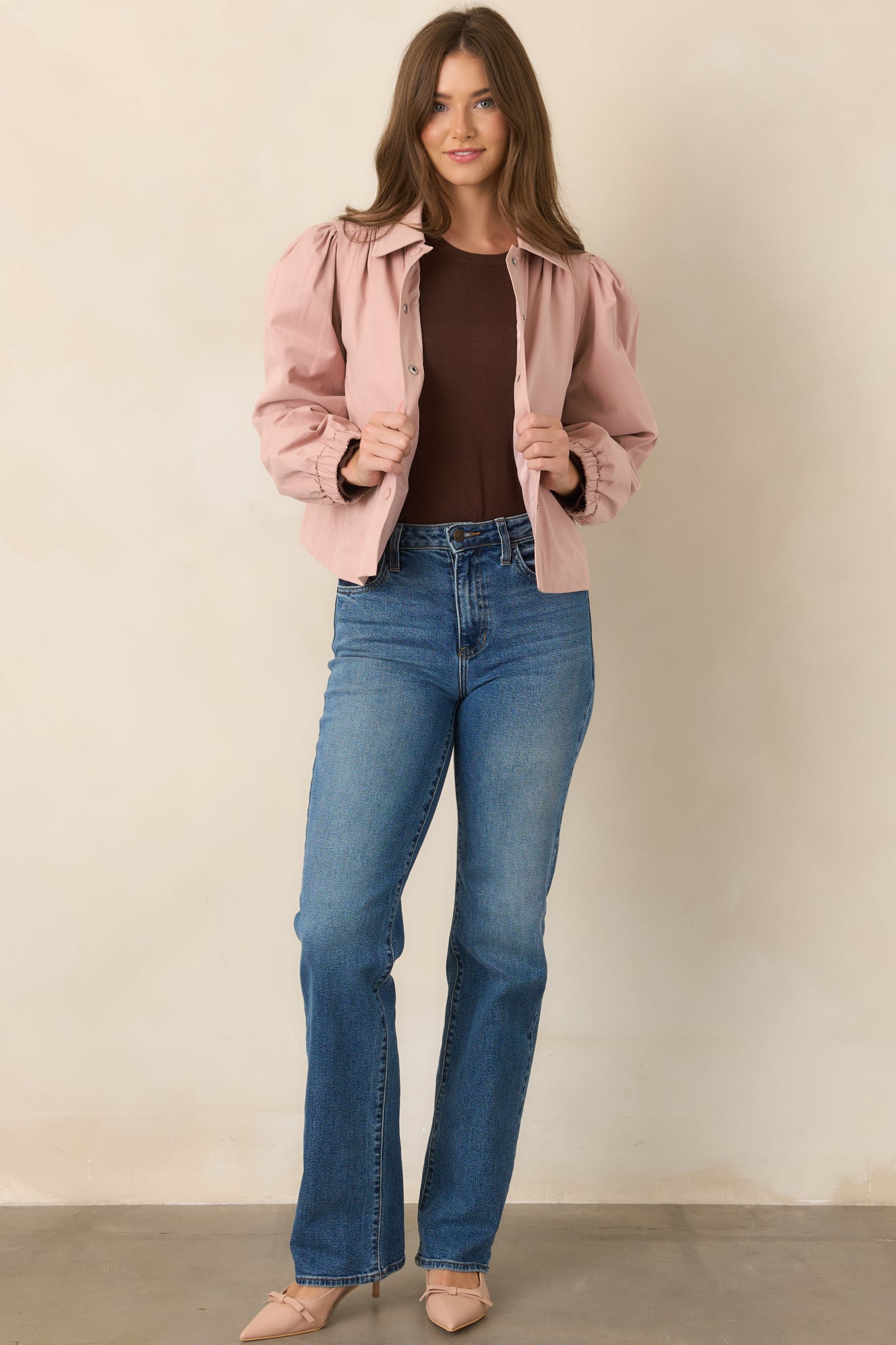 Soft dusty pink jacket with a slightly relaxed cropped silhouette, pointed collar, snap-front design, and softly structured puff sleeves.