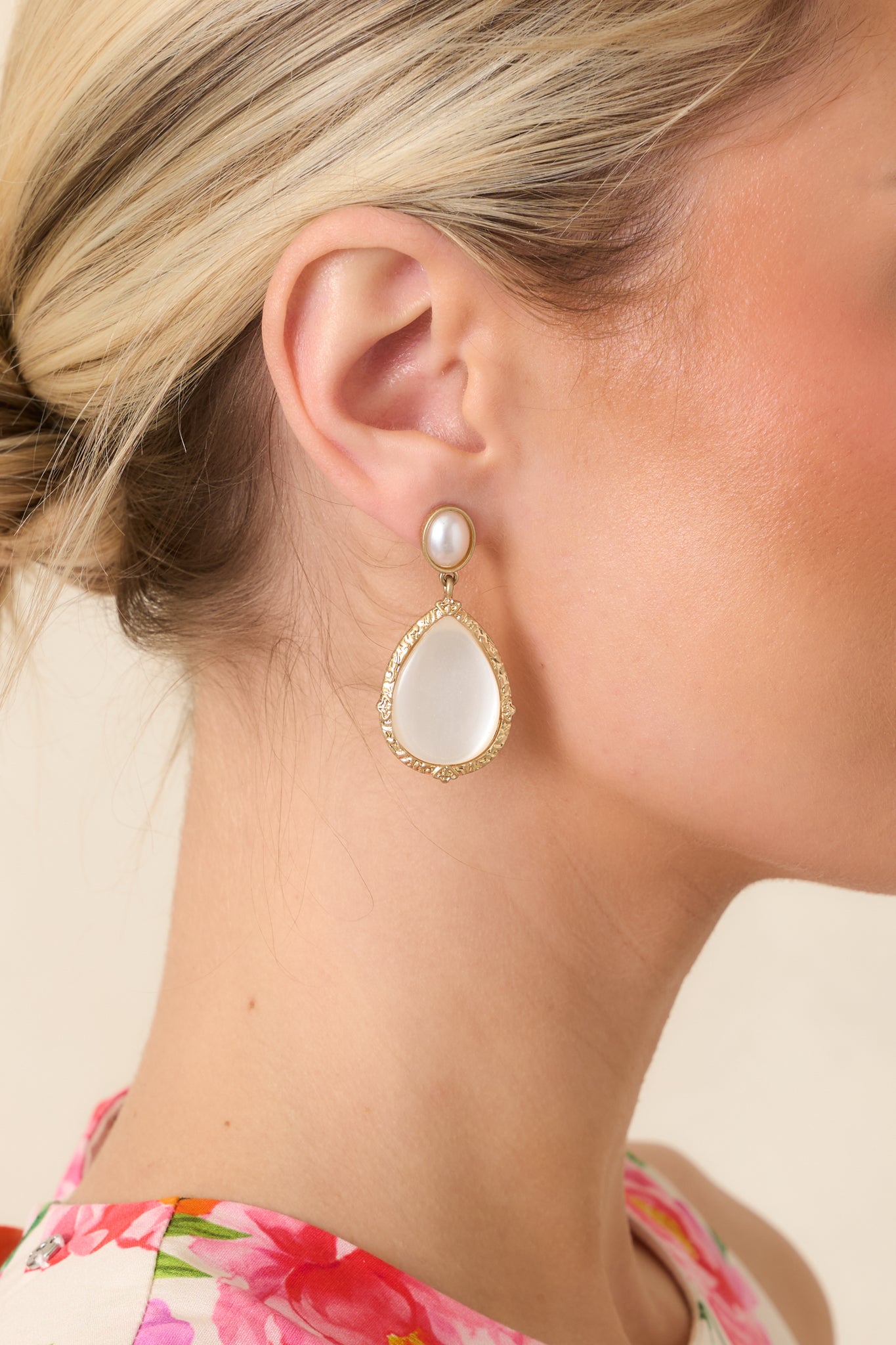 Close-up shot of earrings showing luminous pearlescent teardrop dangling from classic pearl stud.