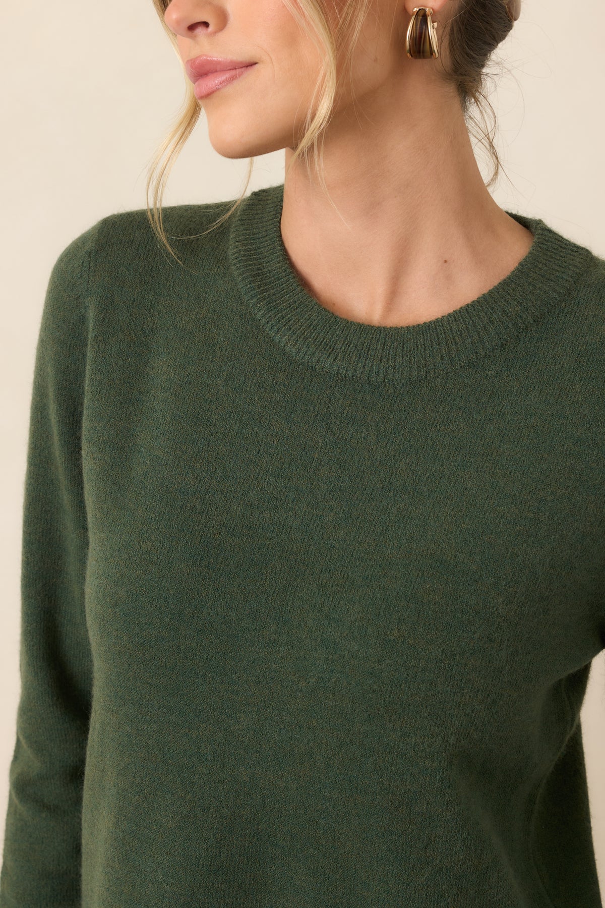 Close view of the earthy green knit texture and ribbed crew neckline.