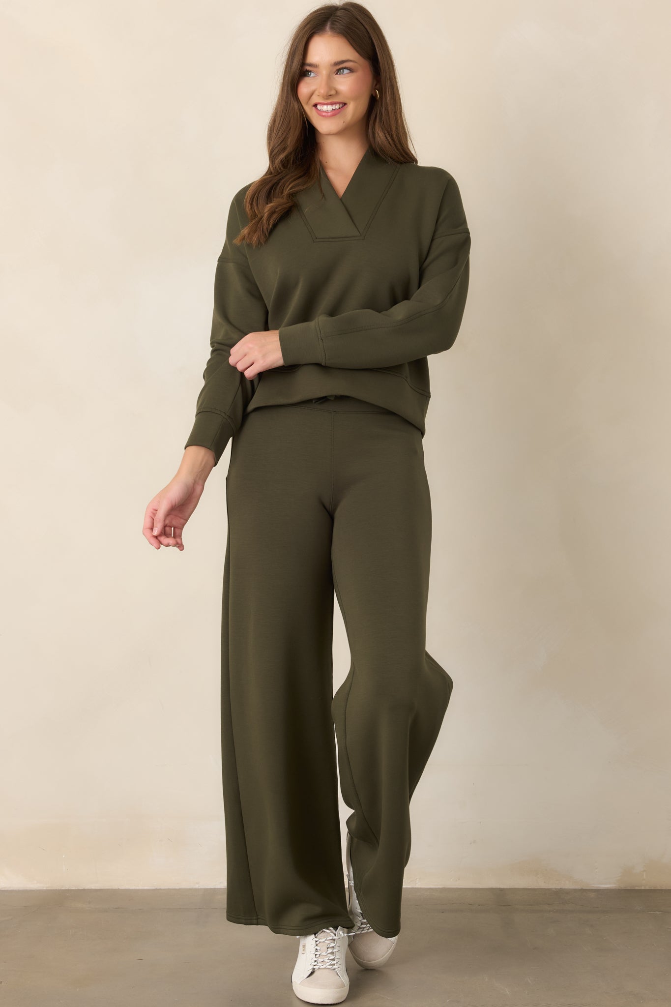 Earthy olive top showcasing its relaxed shape, elongated sleeves, banded cuffs, and clean seamed construction.