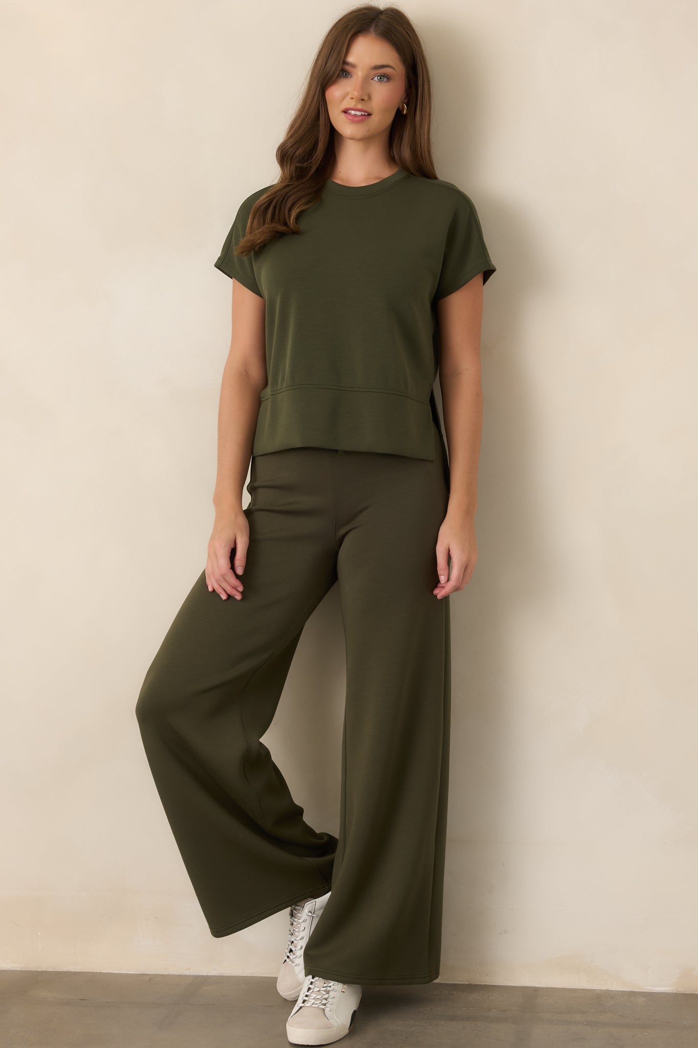 Earthy olive top showcasing its smooth spacer fabric, relaxed silhouette, and high-low hem designed for comfortable movement.