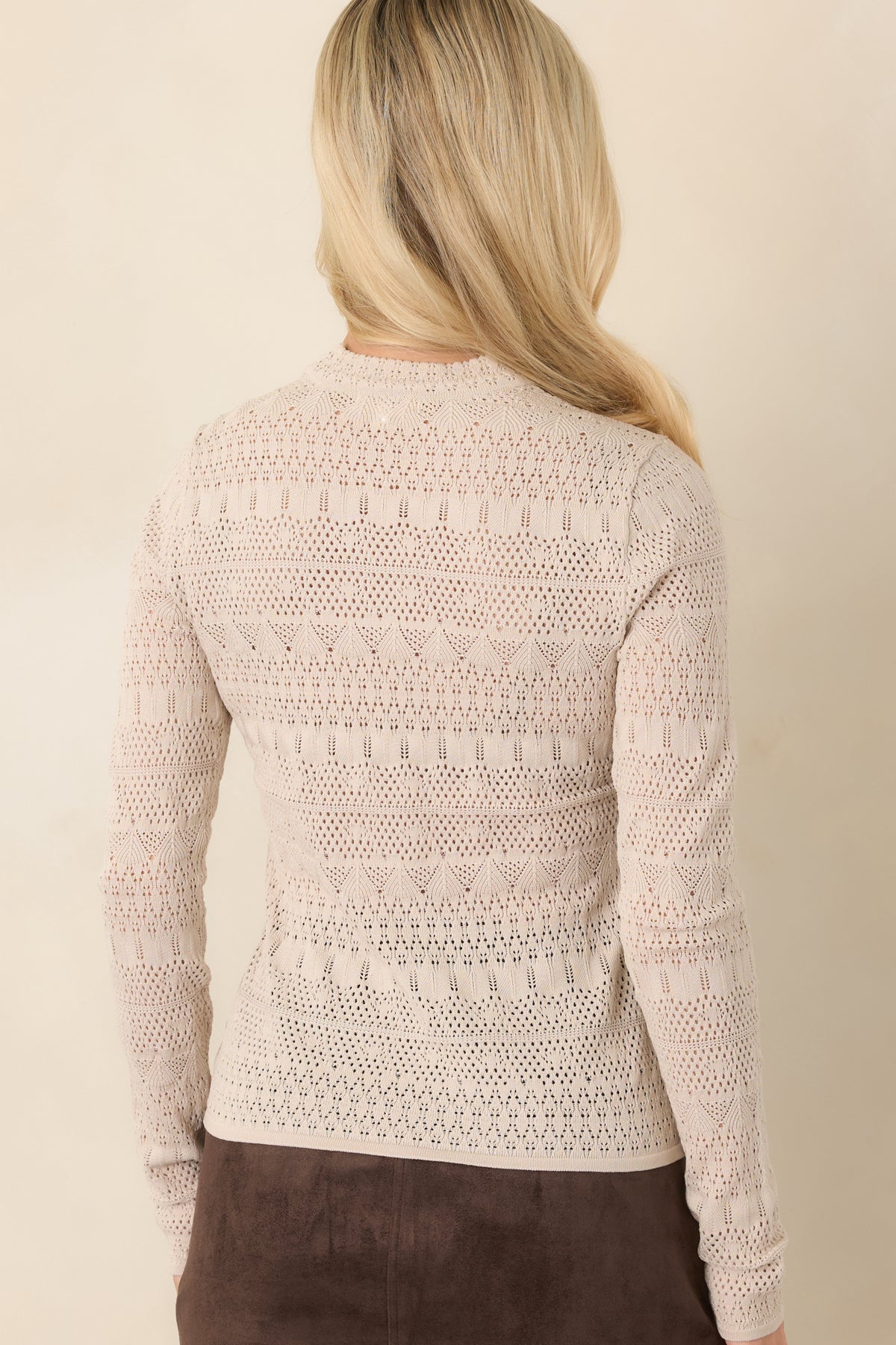 Rear view of the ecru fitted top showing the long sleeves, raised neckline, and geometric pointelle knit pattern.