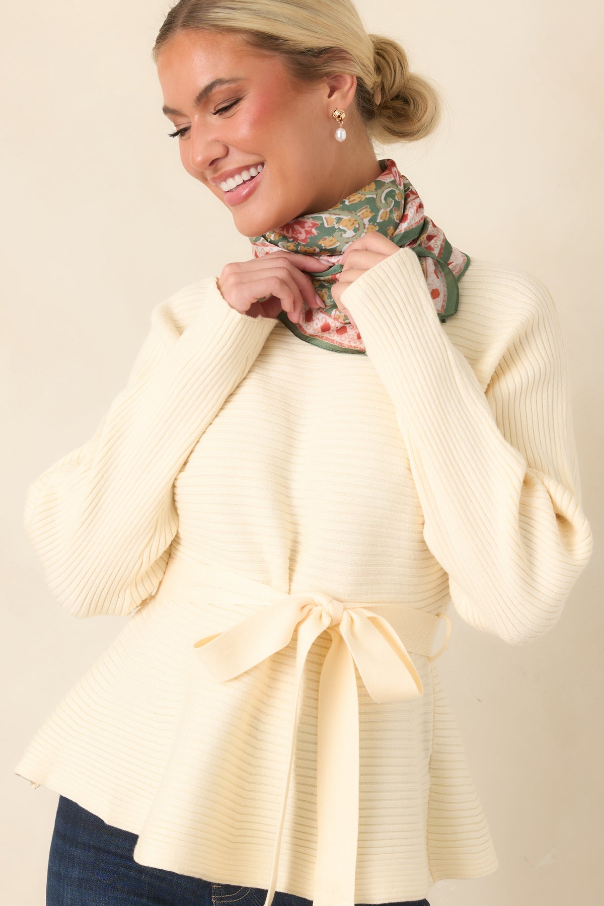 Mock neckline framed by vertical ribbing on the creamy ecru knit top.