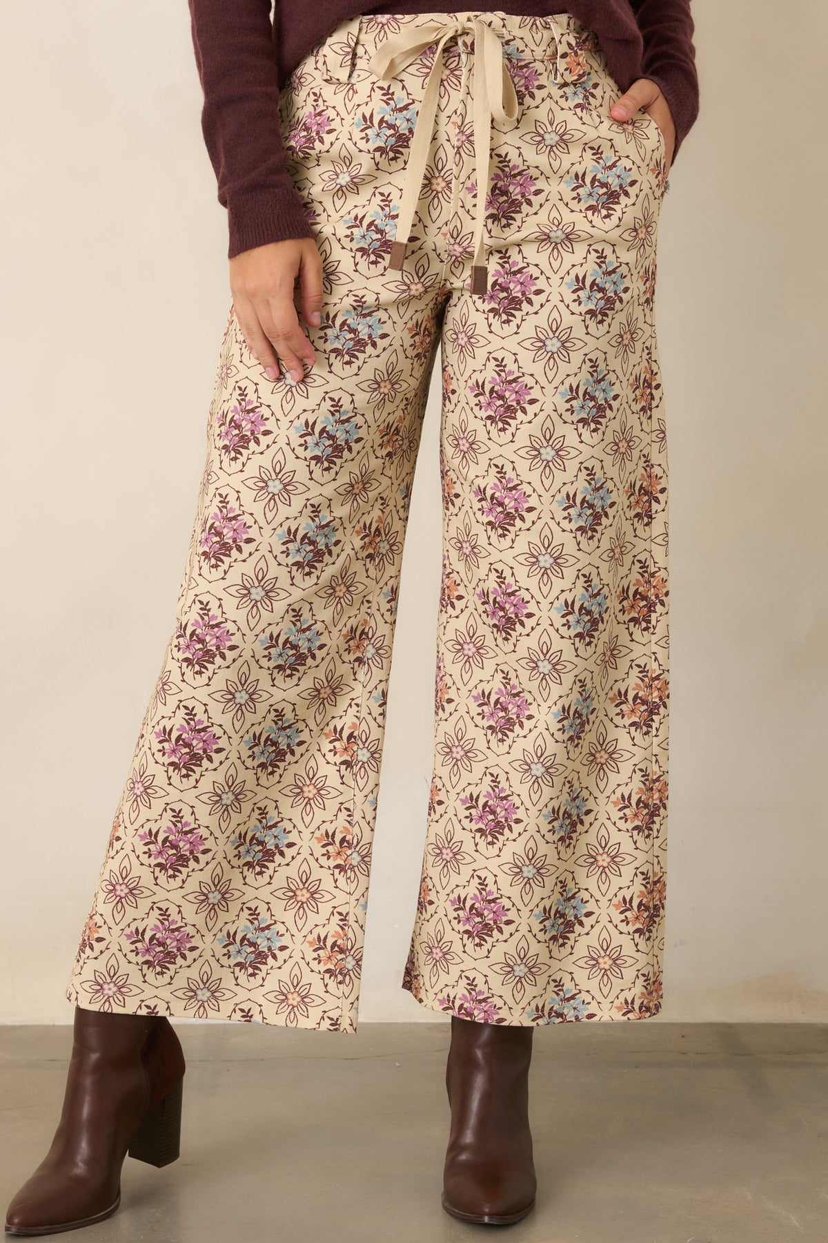 Wide-leg pants displaying muted floral medallions, belt loops, and a front zip fly.