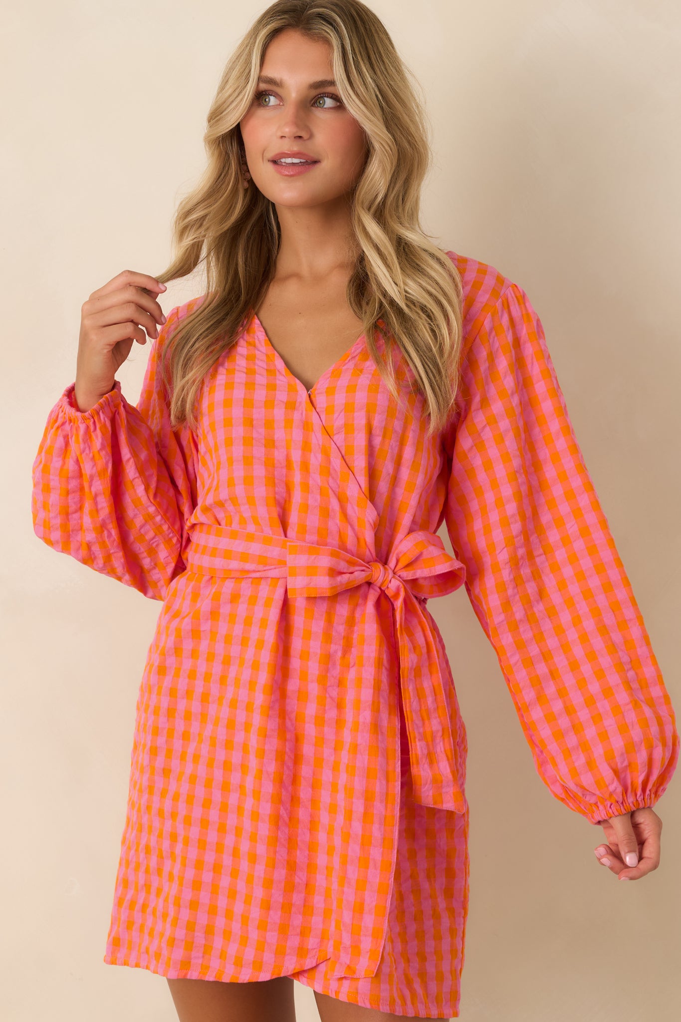 Long sleeves with elastic cuffs add comfortable structure to this lightweight pink and orange gingham wrap dress.