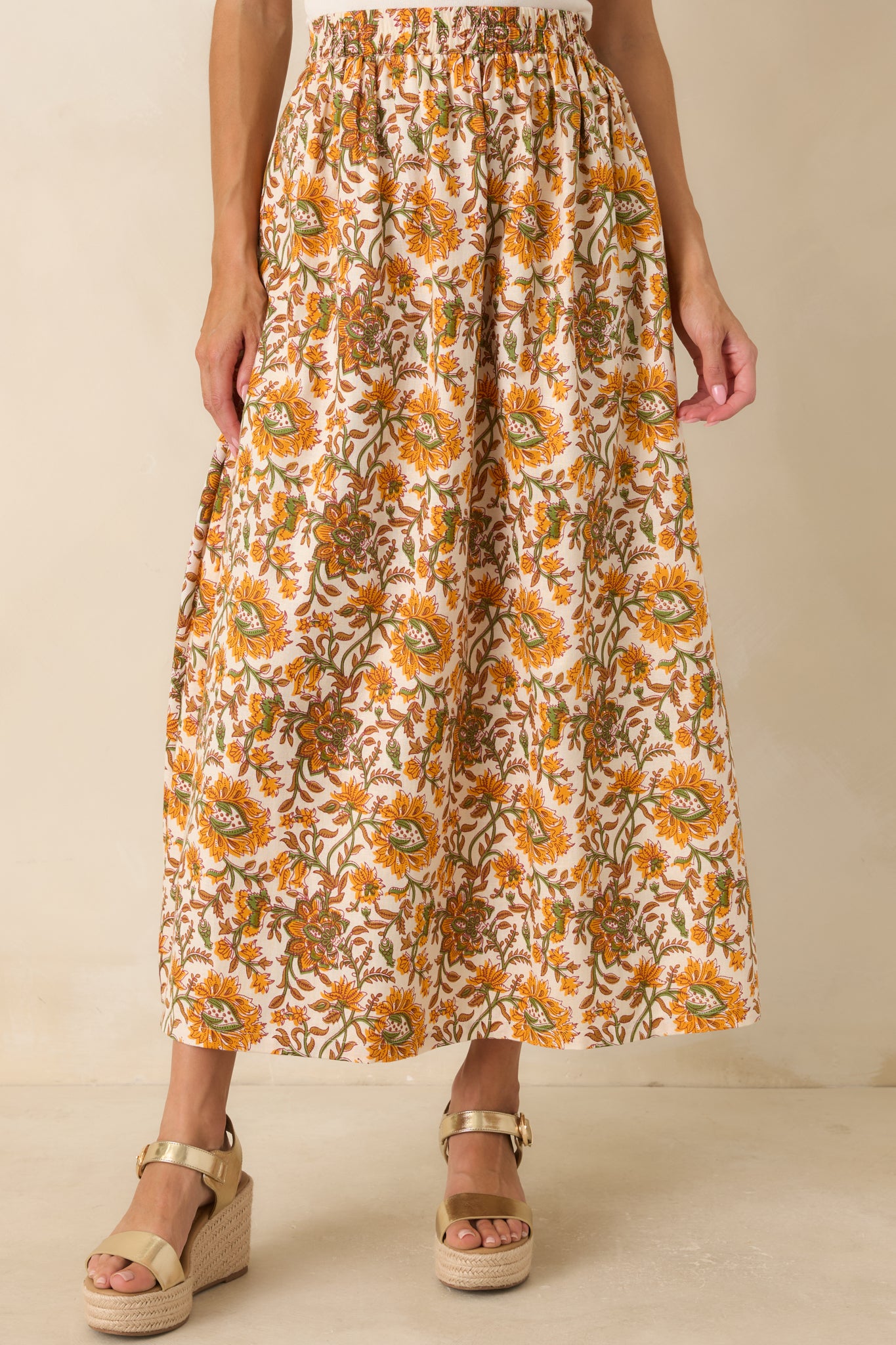 Close view highlighting the elastic waistband and vintage-inspired marigold and olive floral print on the ivory maxi skirt.
