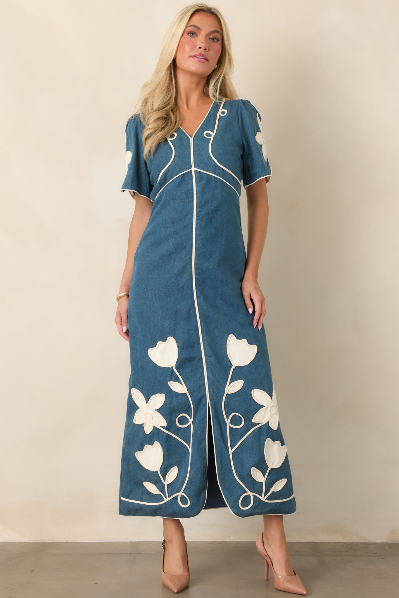 Elegant maxi dress showcasing the V-neckline, short sleeves, ivory floral appliqué, defined waist, and softly flared skirt.