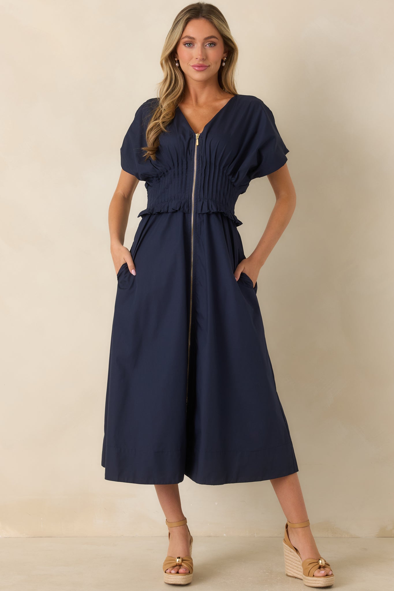 Elegant navy dress with short sleeves, wide smocked waist, and functional side pockets.
