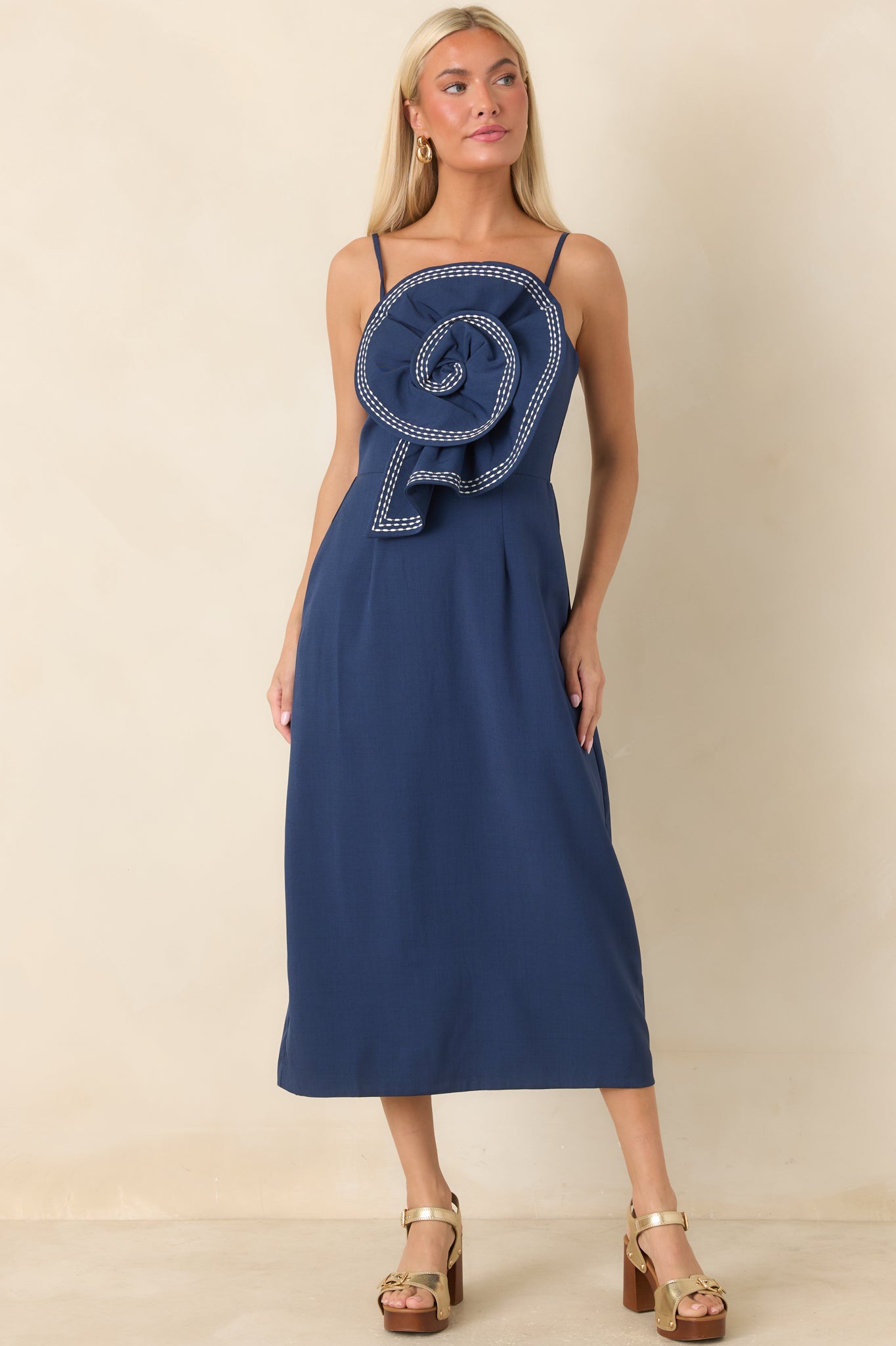 Elegant navy midi dress with adjustable straps, contrast stitching, and a standout front rosette accent.