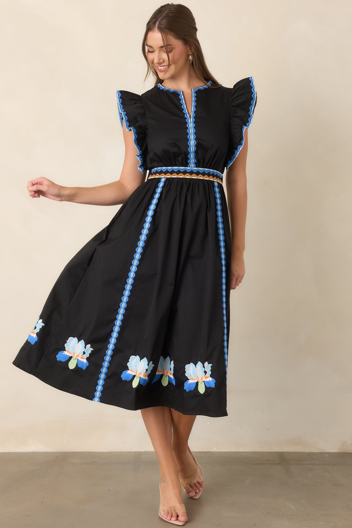 Embroidered black dress featuring blue iris blooms near the hem.