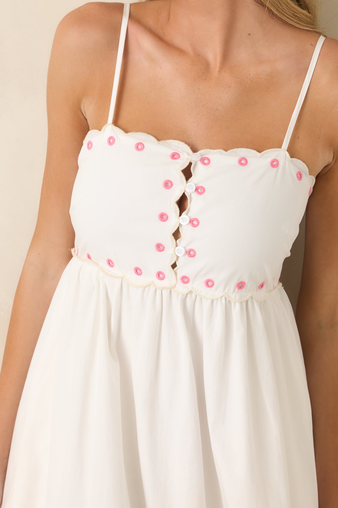 Detailed view of the embroidered bodice, peek-a-boo button-front, scalloped neckline, and floral cutwork trim.