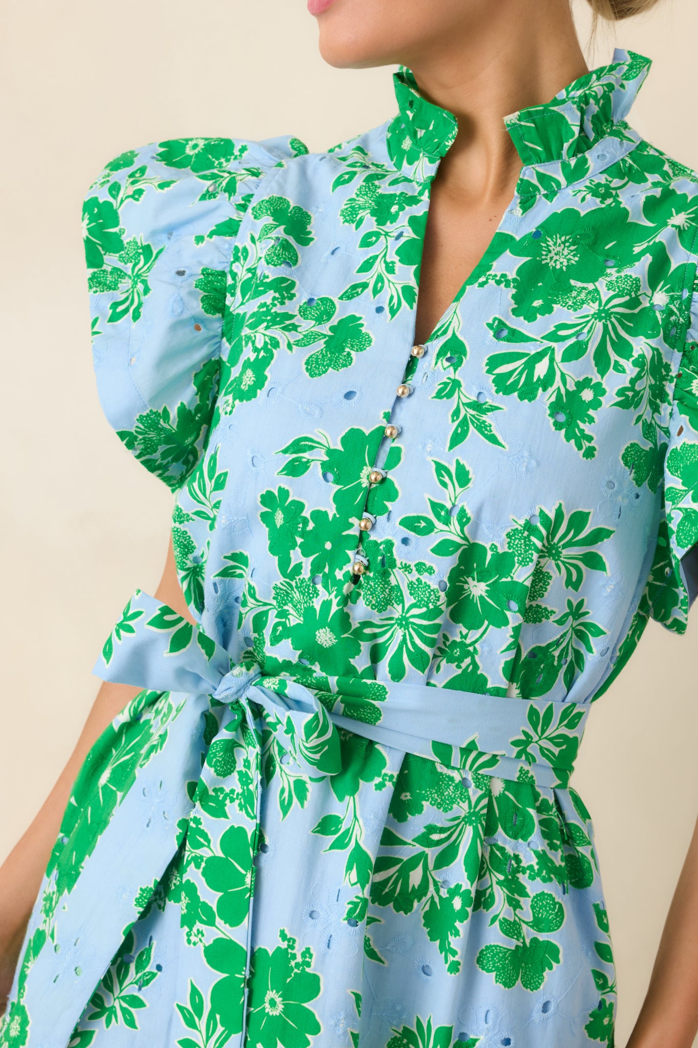 Embroidered eyelet fabric with textured floral design and ruffle hem detail.