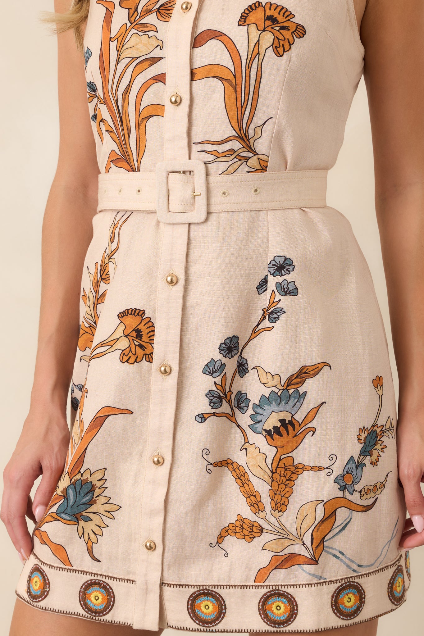 Close-up of the embroidered border hem and colorful floral print against the ivory cotton-linen fabric.